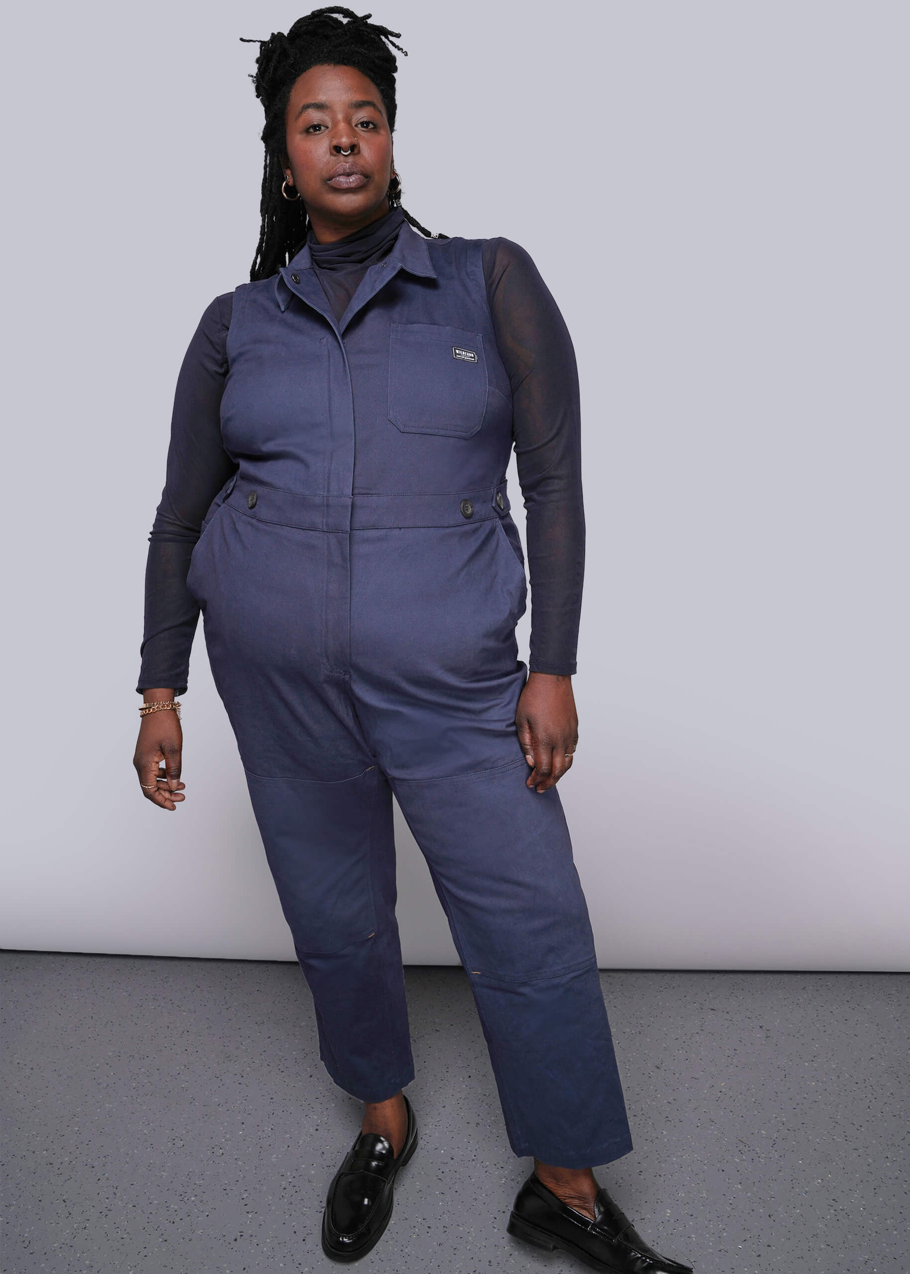 1X=Person wearing a blue jumpsuit with a plain background