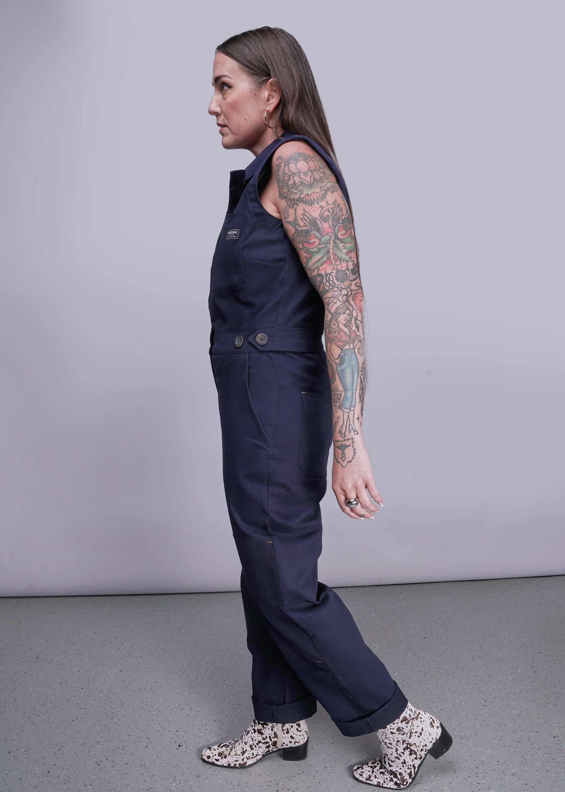 S=Person wearing a navy blue jumpsuit with floral shoes on a gray background