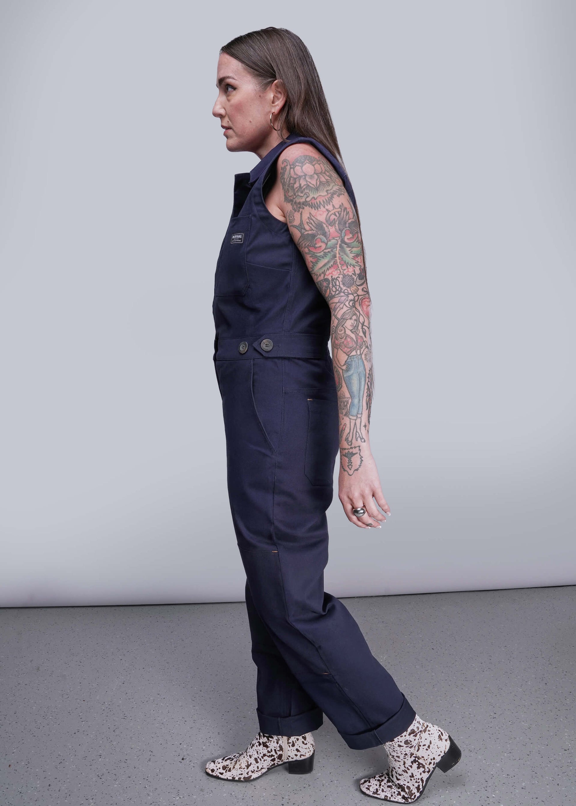 S=Person wearing a navy blue jumpsuit with floral shoes on a gray background