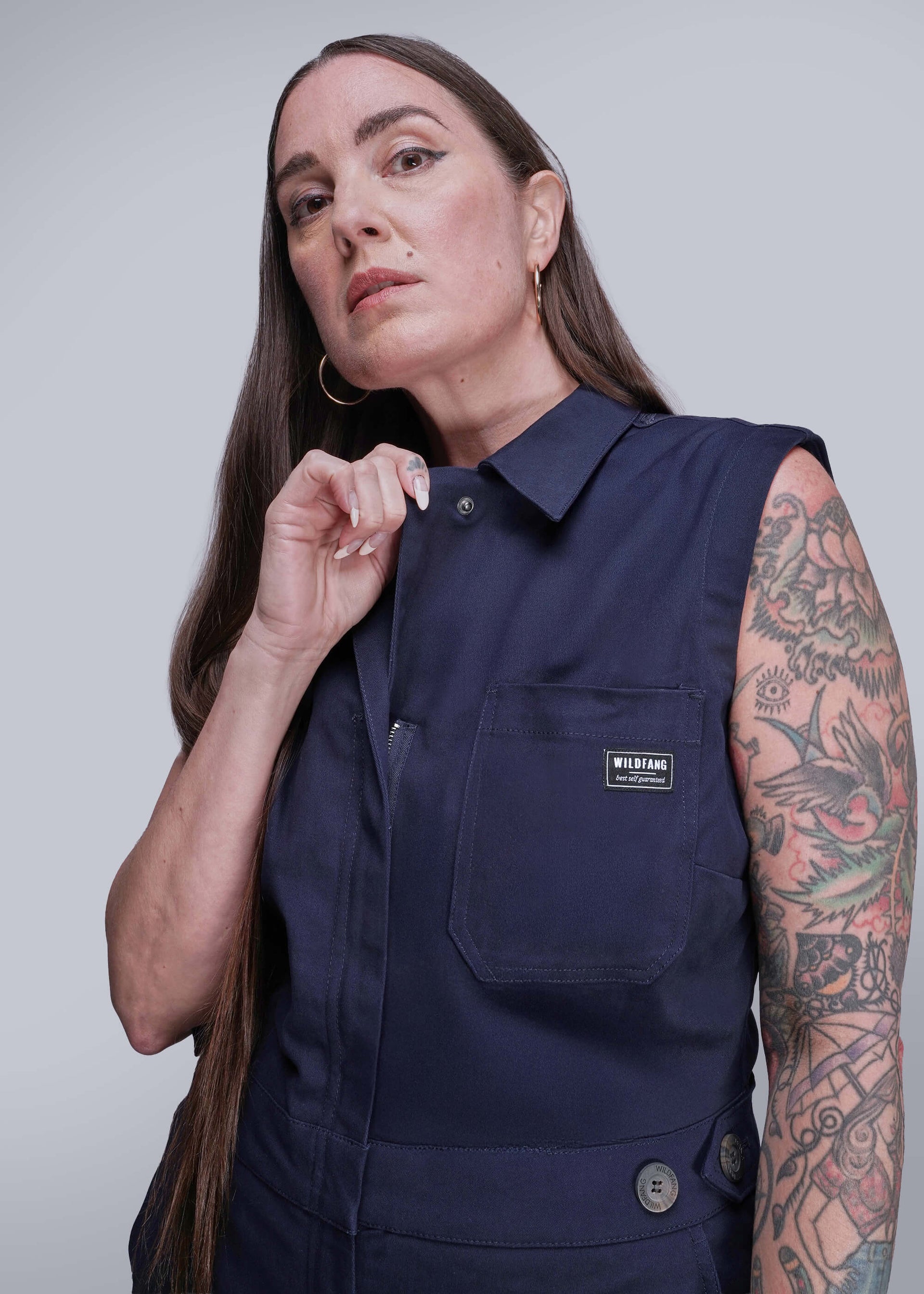 S=Woman wearing a navy sleeveless shirt with a visible brand label on a plain background