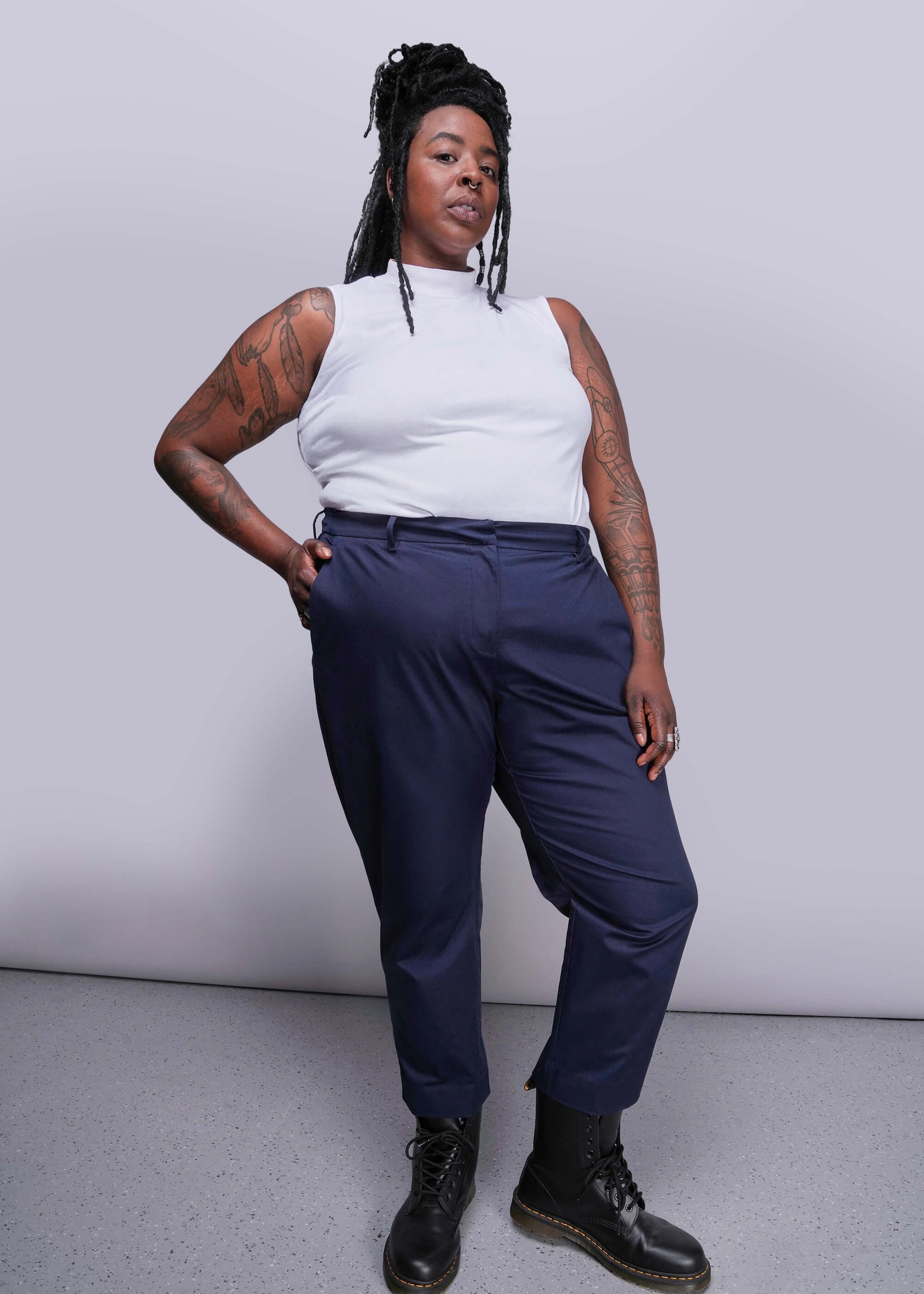 1X=Person wearing a white sleeveless top and navy pants against a plain background
