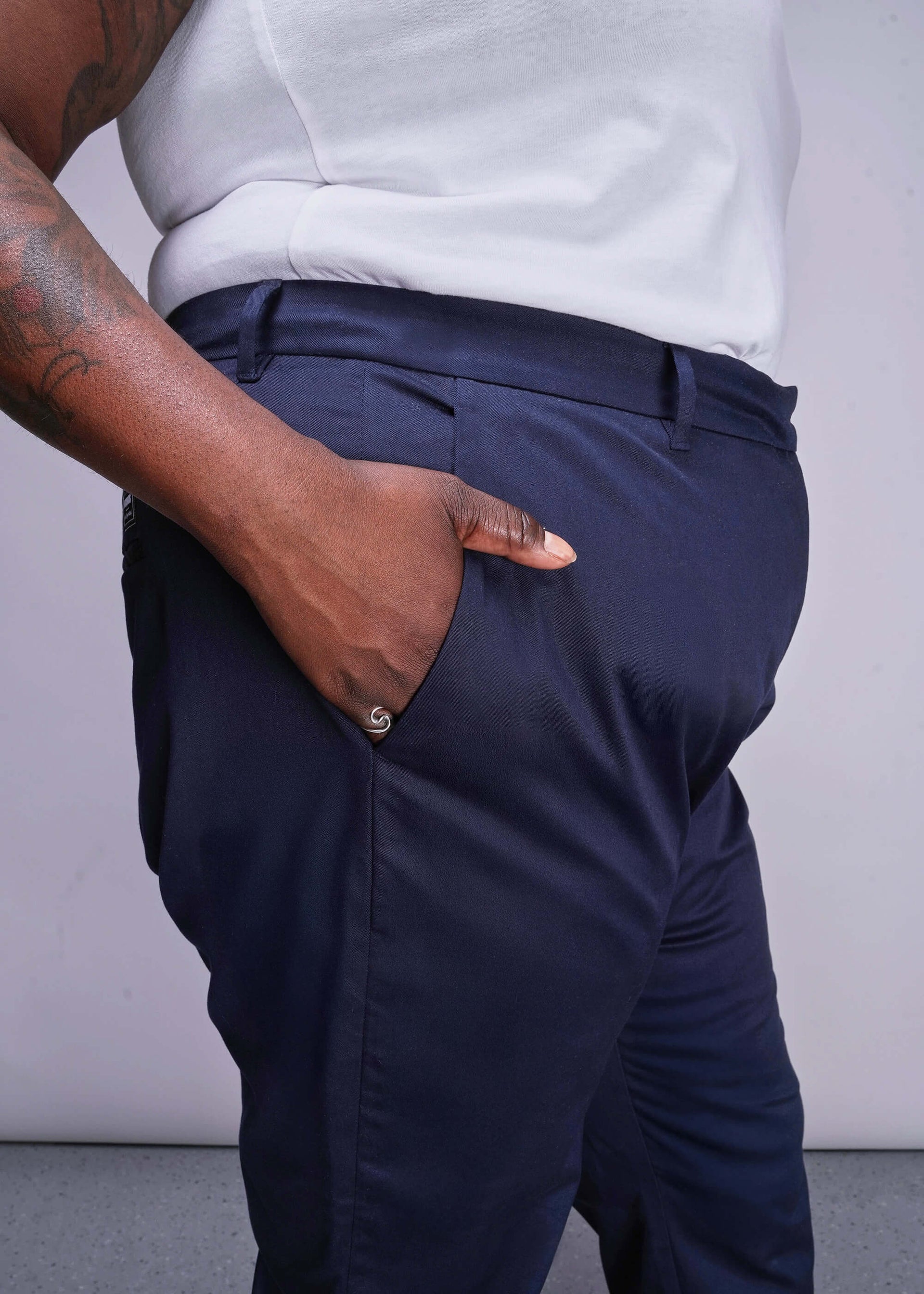 1X=Person wearing navy pants and a white shirt against a plain background