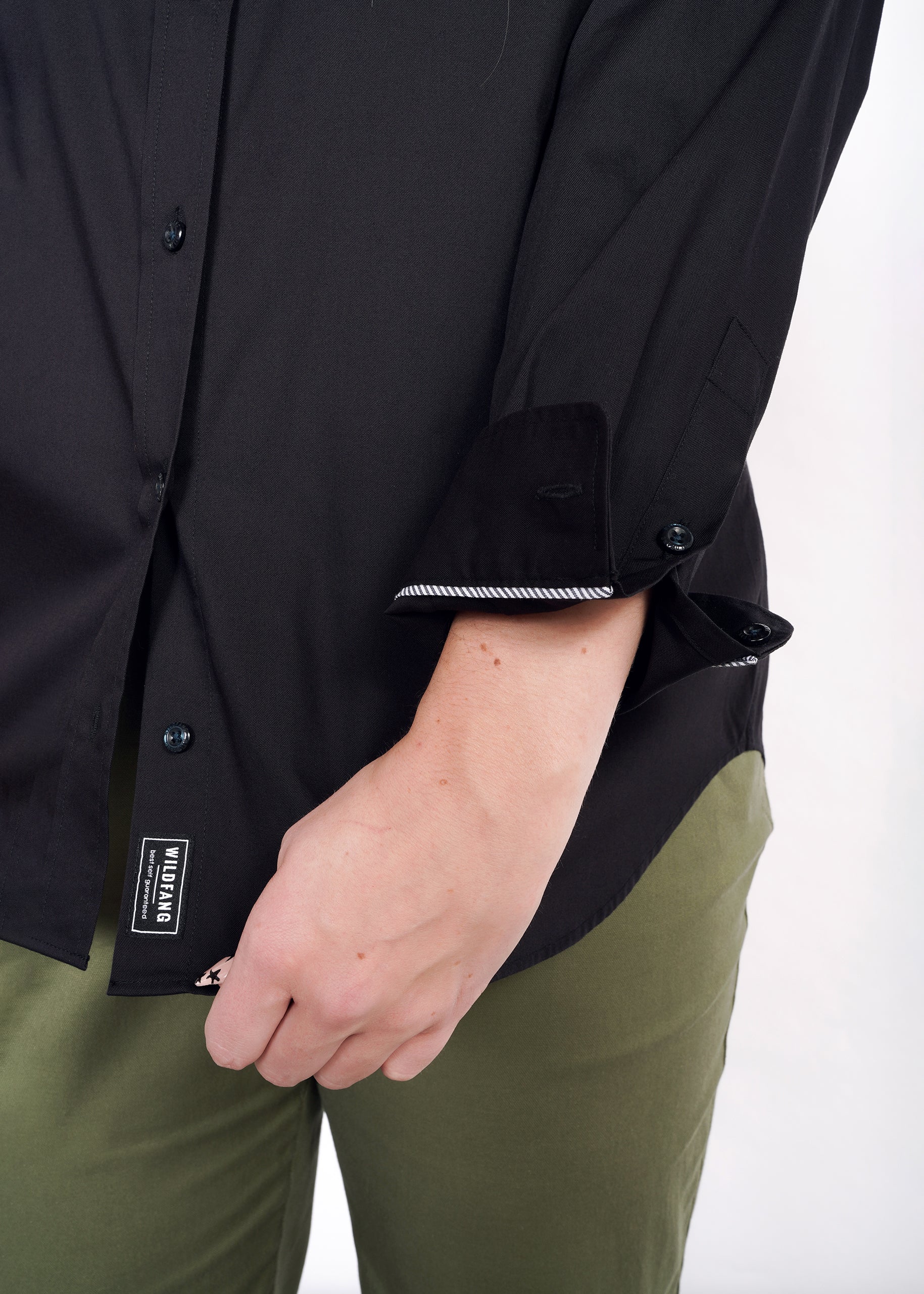 S=Detail shot of black button up interior patch that reads "WILDFANG | best self guaranteed"