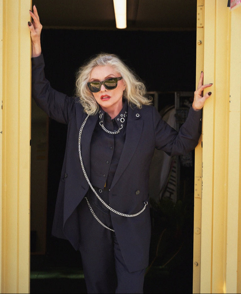 Person in a dark suit and sunglasses standing in a doorway.
