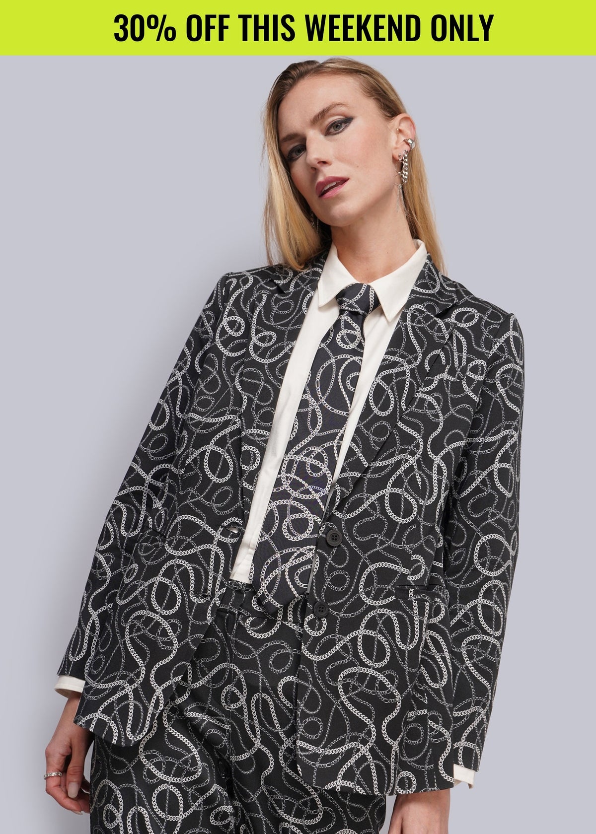 Person wearing black printed suit with white button up and matching tie. Promotional banner on top of image reads 30% OFF THIS WEEKEND ONLY