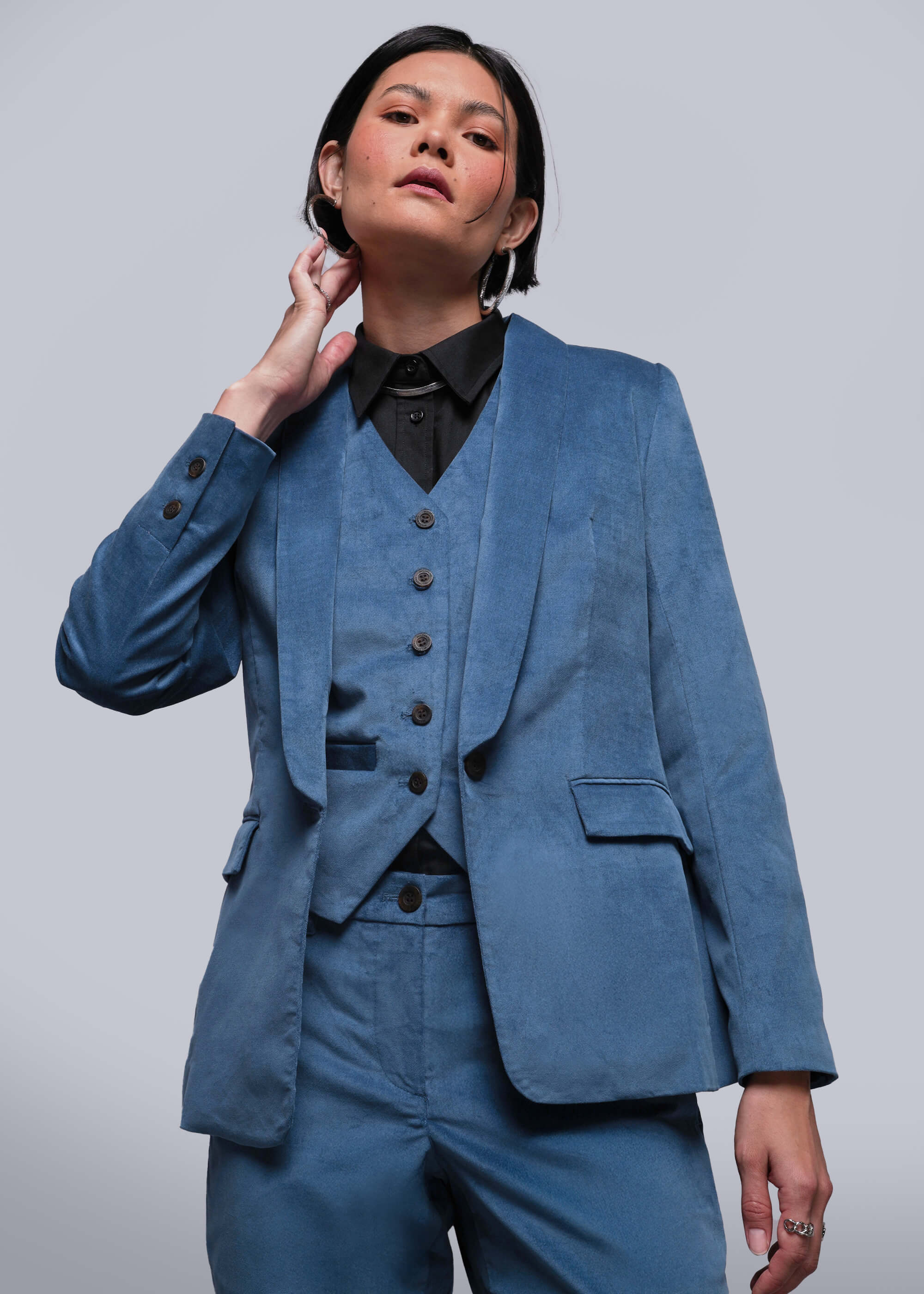 Person wearing a blue suit with a black shirt against a plain background
