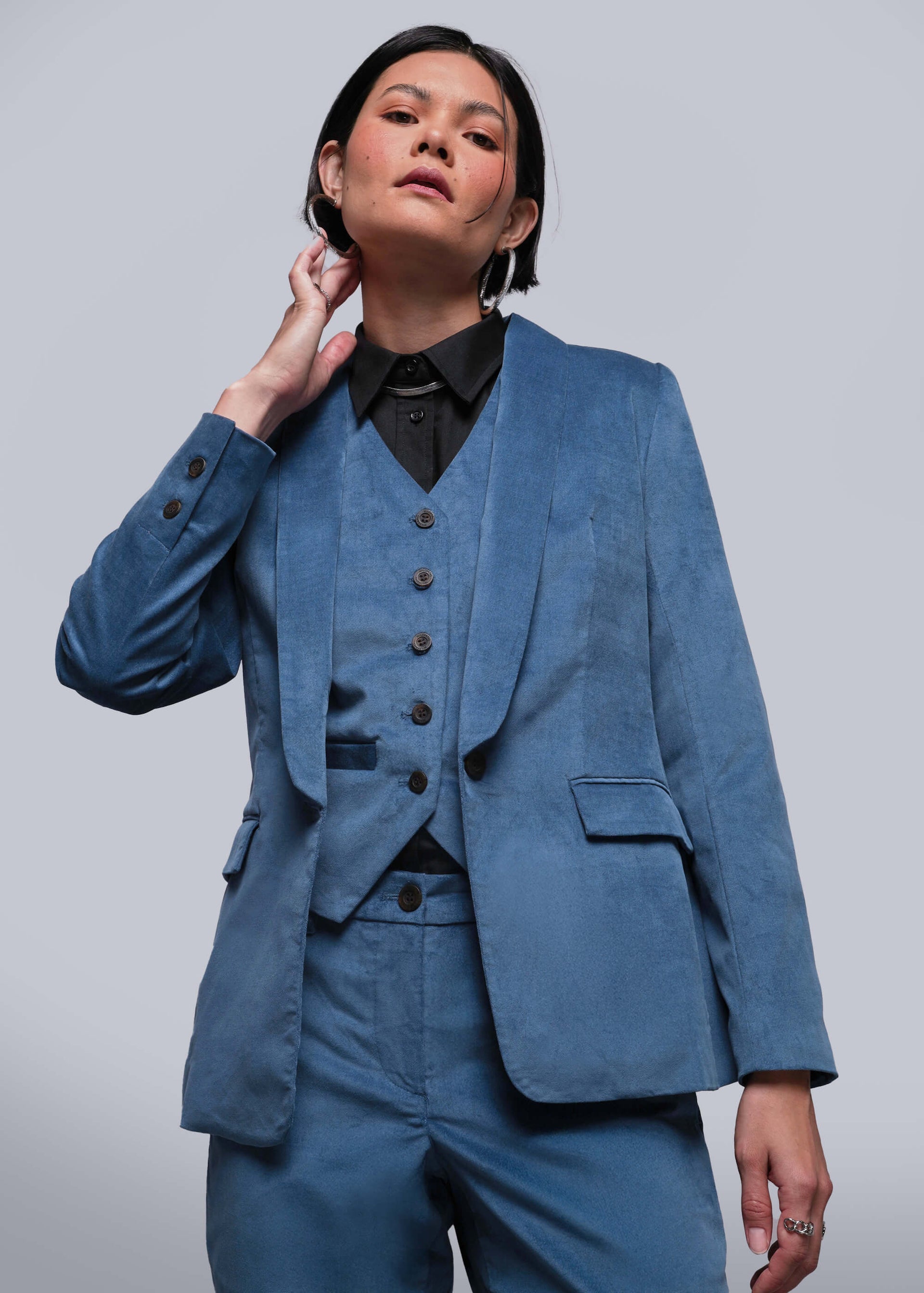 S=Person wearing a blue suit with a black shirt against a plain background