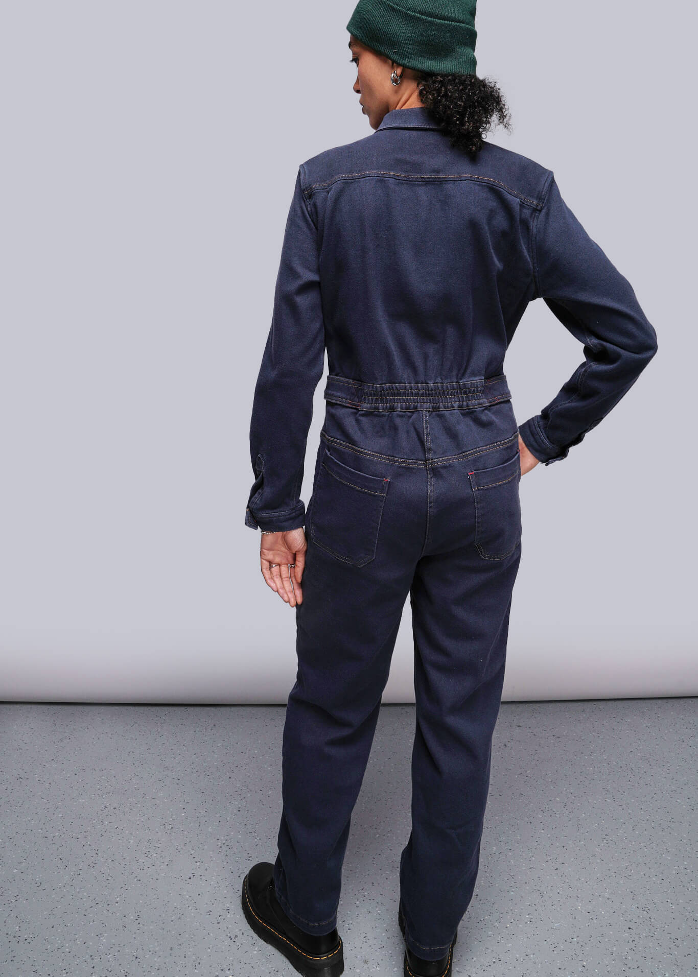 S=Person wearing a navy blue coverall against a gray background