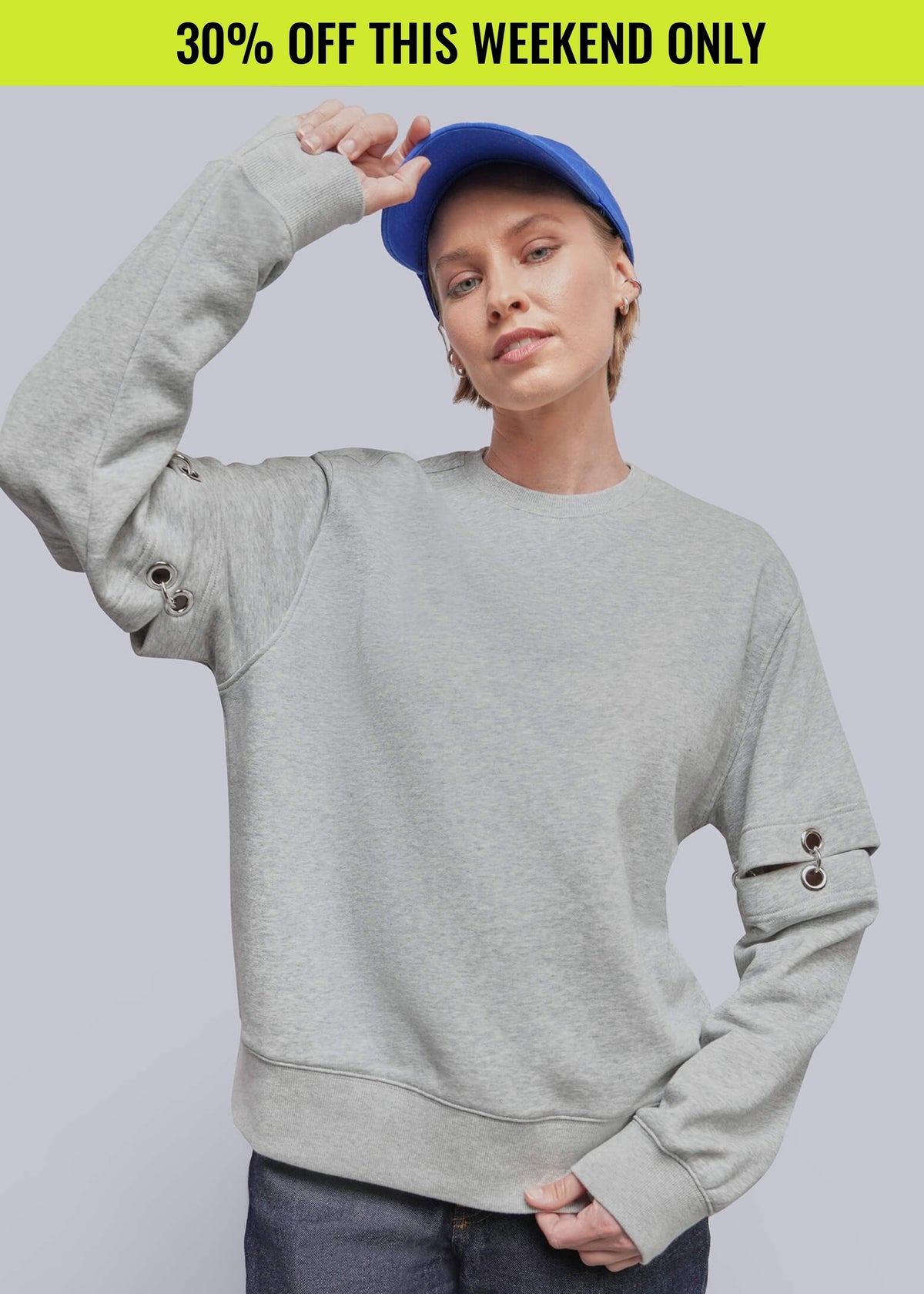 Person wearing blue hat, grey sweatshirt with metal ring details at the elbows, and jeans. Promotional banner on top of image reads 30% OFF THIS WEEKEND ONLY
