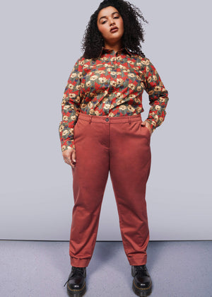 1X=Person wearing a floral shirt and red pants against a white background