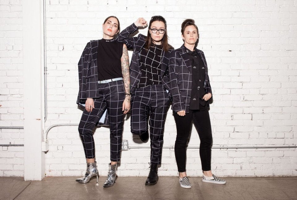 Emma McIlroy, Julia Parsley and Taralyn Thuot, founders of Wildfang, wearing black and white suits standing in front of white brick wall
