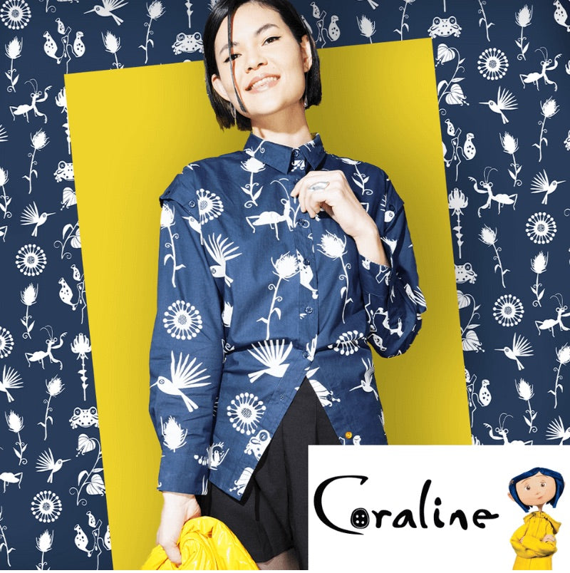 Woman wearing a blue patterned blouse with a yellow background and 'Coraline' branding.