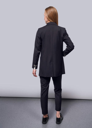S=A woman with long hair, facing away on a neutral background, wears a Debbie Harry X Wildfang Double Breasted Blazer with matching pants, complemented by black shoes with metal detailing.