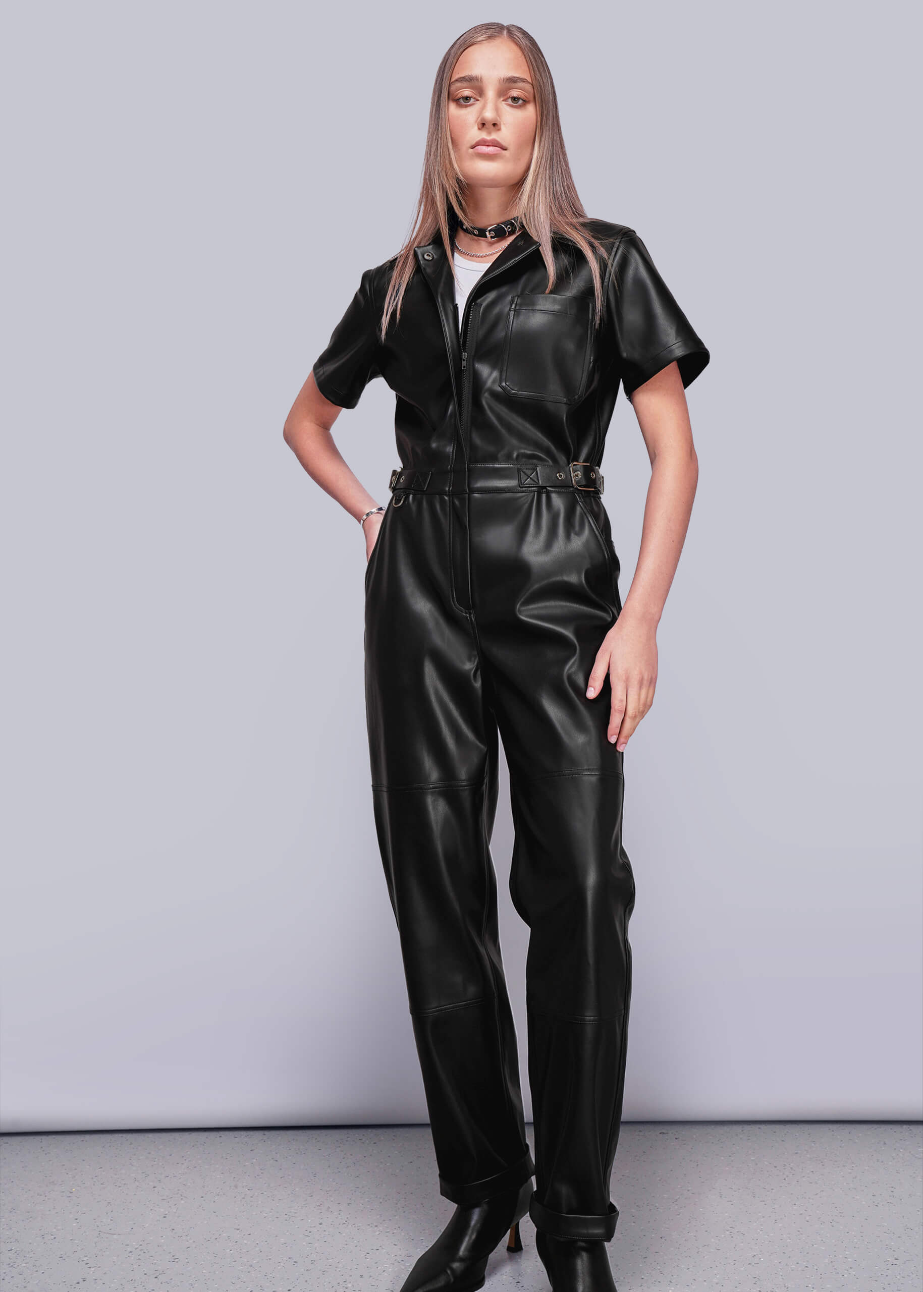 Person wearing a black vegan leather jumpsuit against a plain background