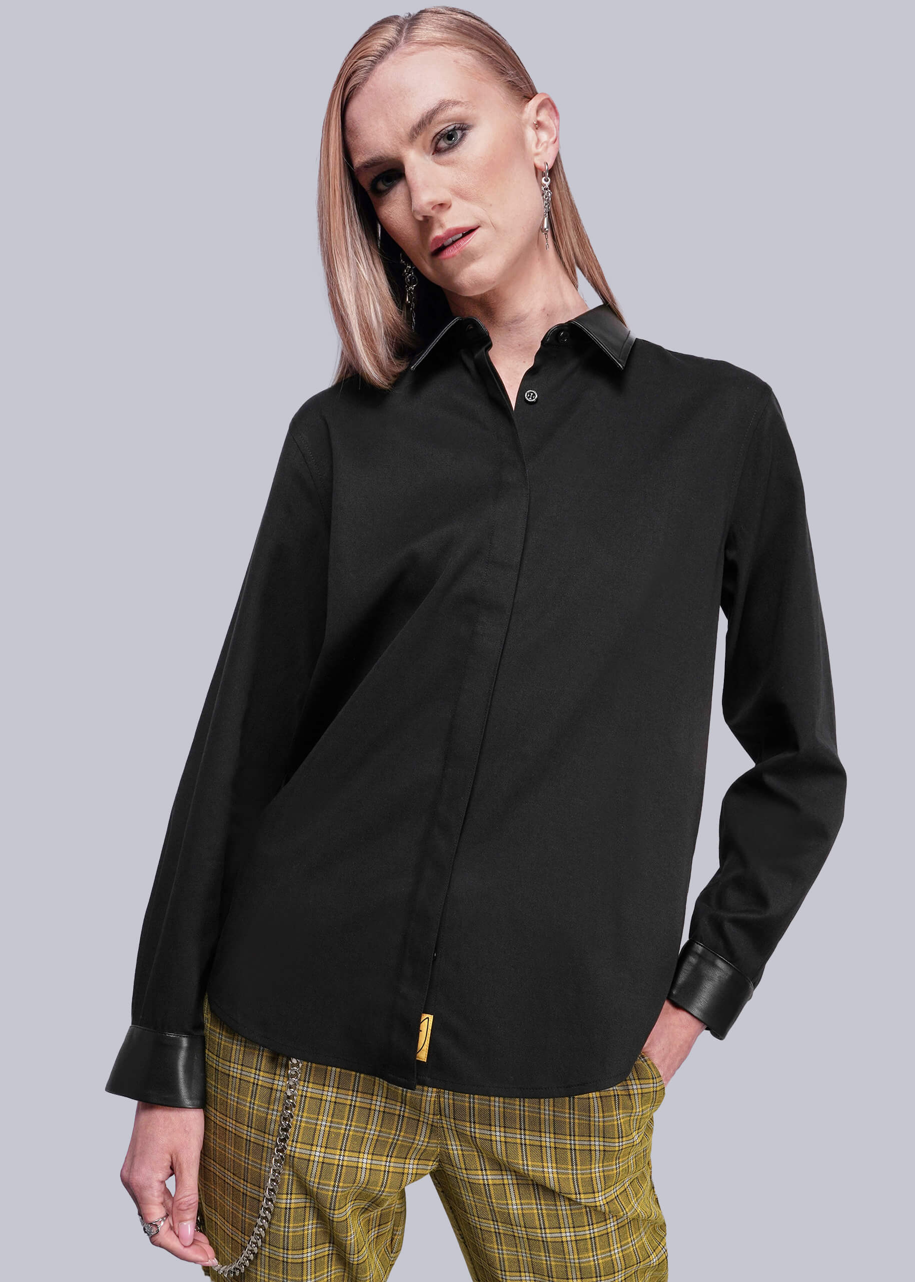 Person wearing a black shirt with vegan leather collar and cuffs on a gray background