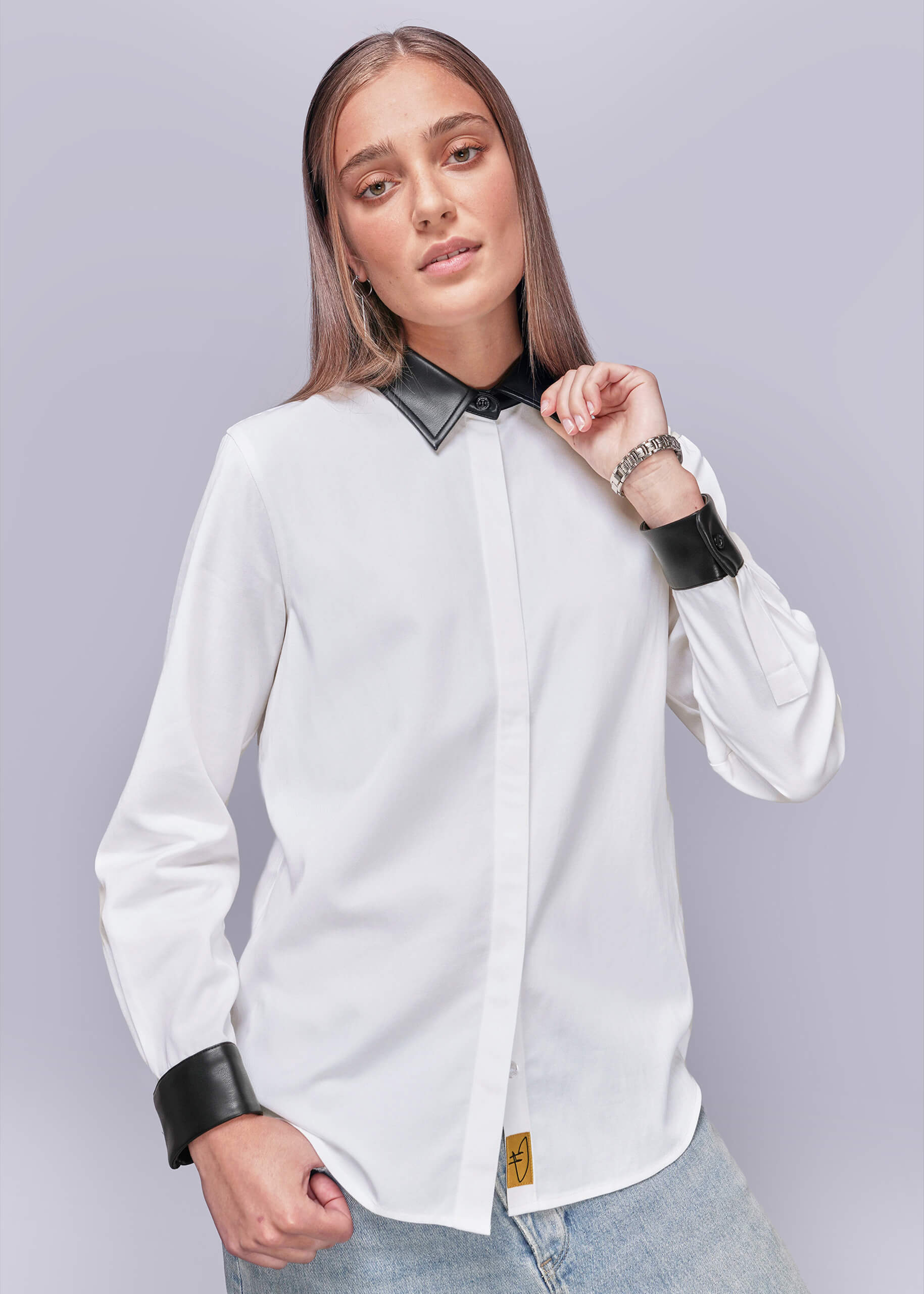 S=Person wearing a white shirt with black vegan leather collar and cuffs on a light gray background