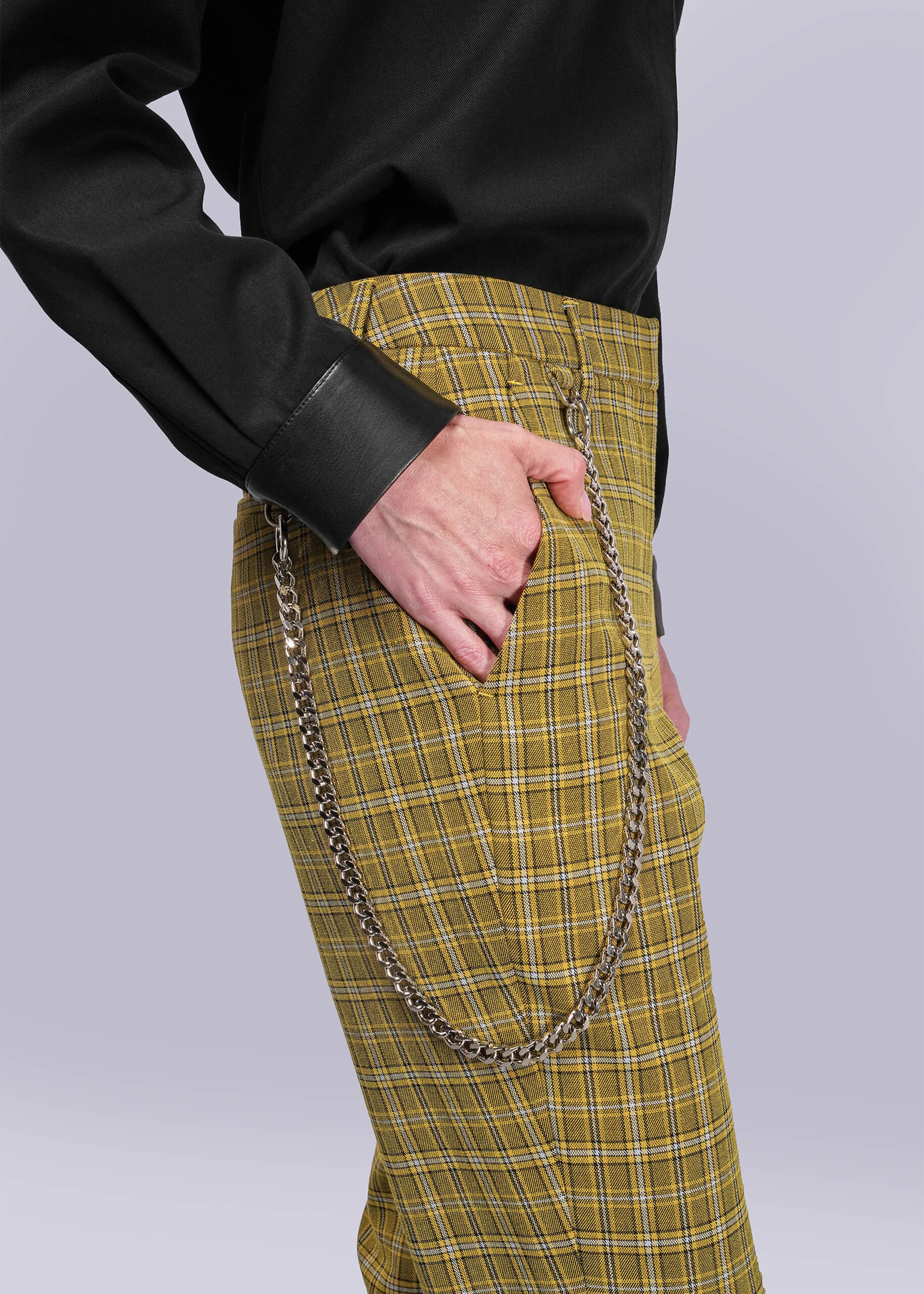 S=Person wearing yellow plaid pants with a black button up on a light gray background