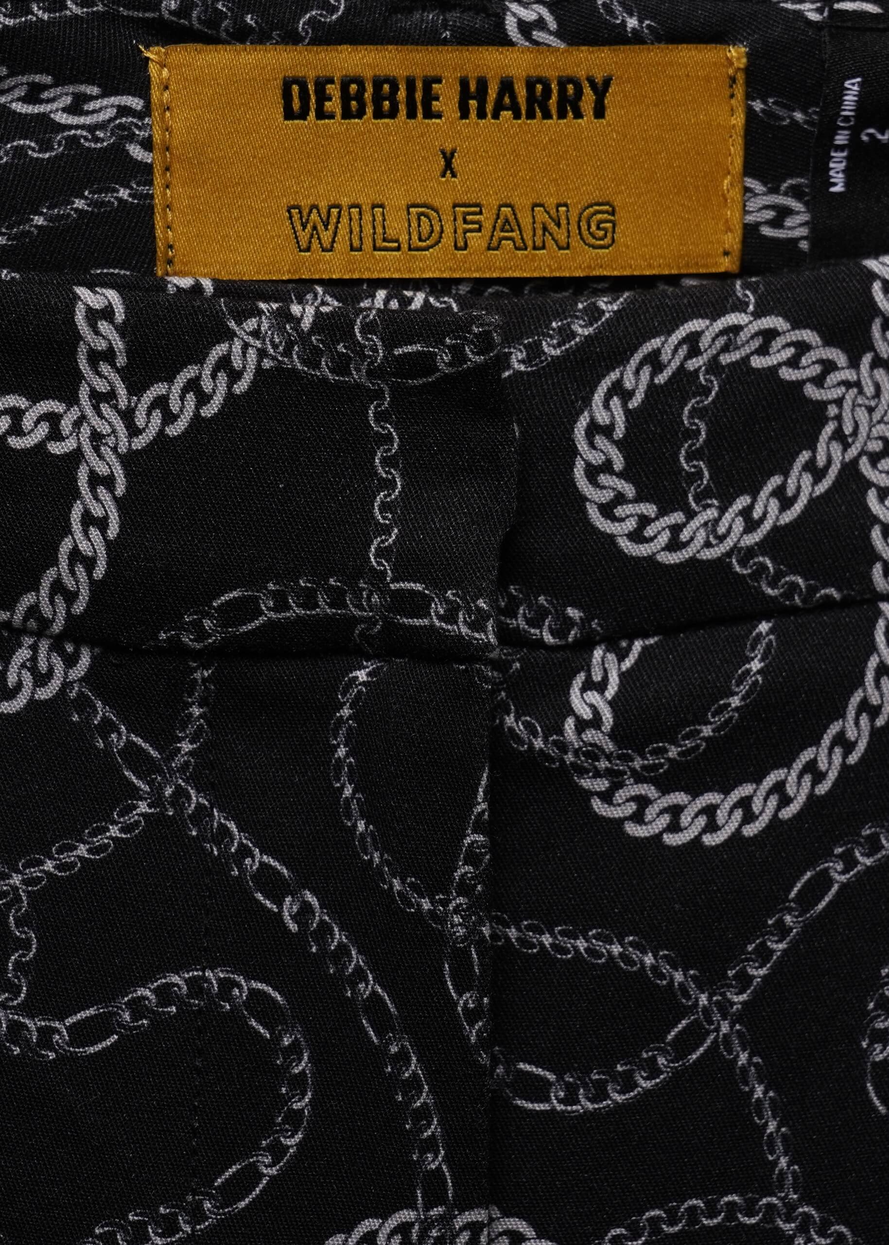 Close-up of black fabric with a white chain pattern and a yellow label reading 'DEBBIE HARRY x WILDFANG'.