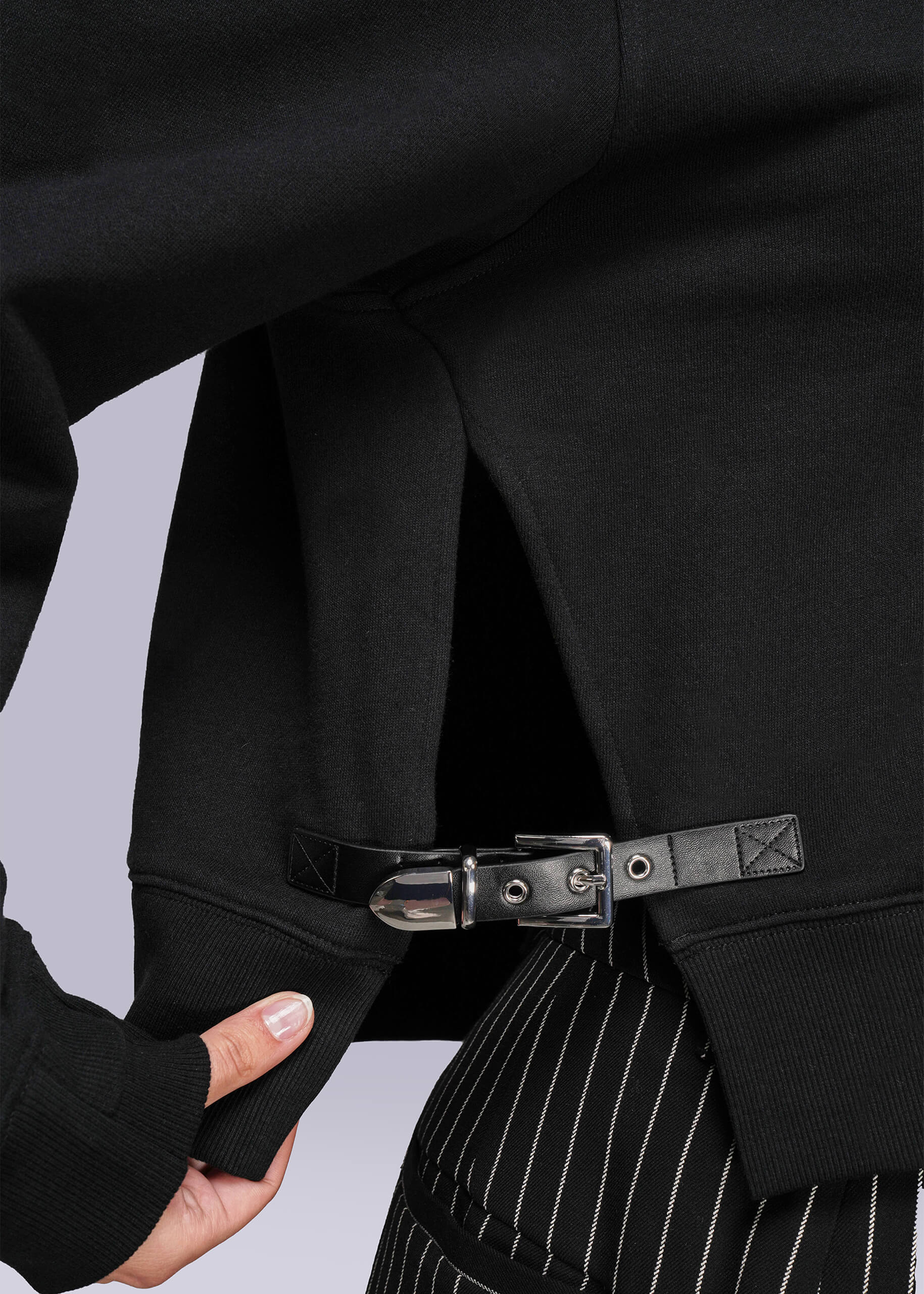S=Close-up of a sweatshirt with buckle and pinstripe pants on a light gray background