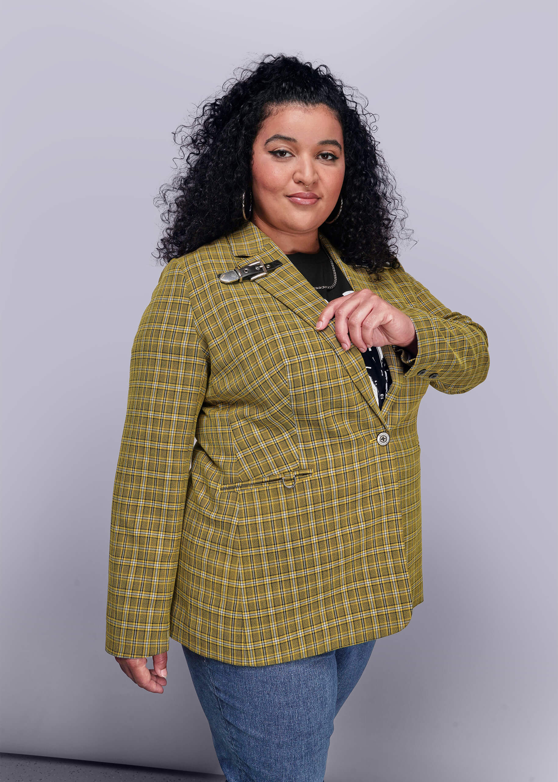 1X=Side view of person wearing a yellow plaid blazer against a gray background