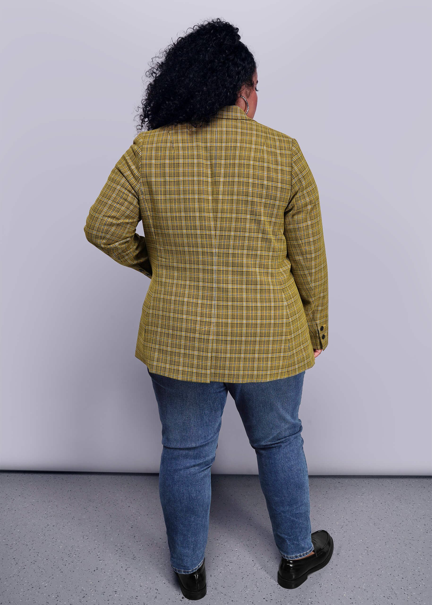 1X=Back view of person wearing a yellow plaid jacket and blue jeans against a white background