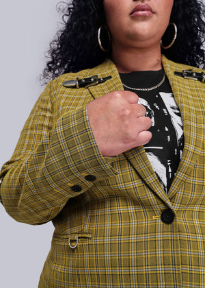 1X=Close up view of person wearing a yellow plaid jacket with black buttons on a plain background