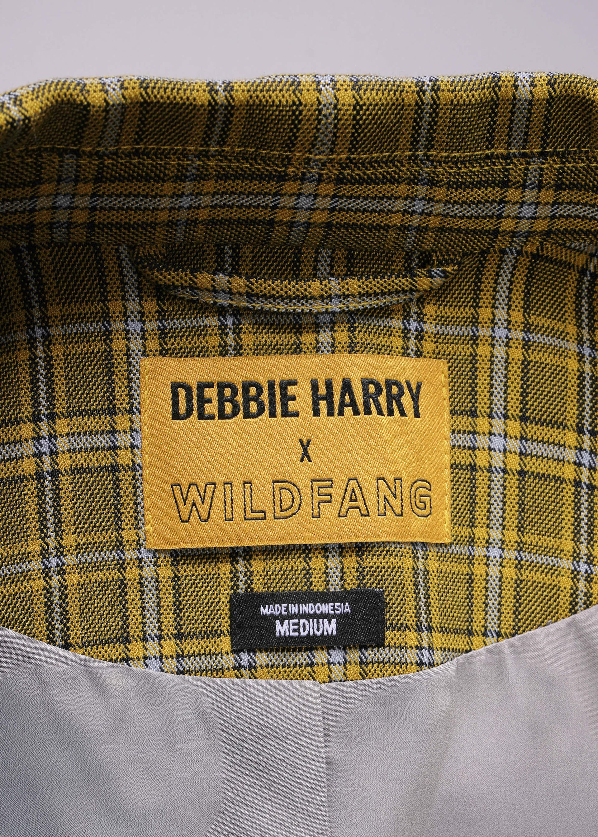 Plaid fabric with a label reading 'Debbie Harry x Wildfang' on a gray background