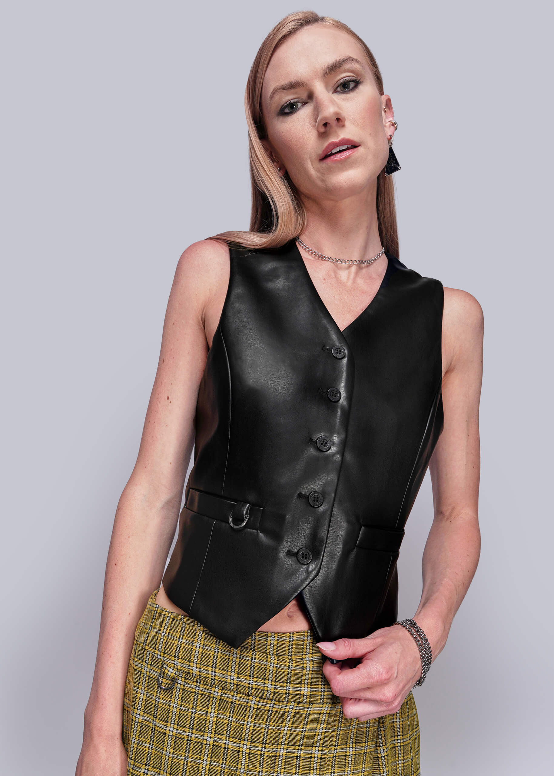 Peraon wearing a black vegan leather vest against a plain background