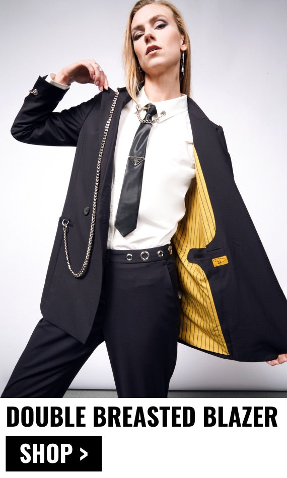 Person with long blonde hair wears the Debbie Harry x Wildfang Double Breasted Blazer with one side open showing the yellow lining. Text underneath image reads DOUBLE BREASTED BLAZER $198 with a black button underneath that says SHOP.