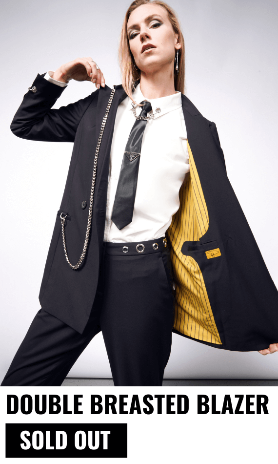 Person with long blonde hair wears the Debbie Harry x Wildfang Double Breasted Blazer with one side open showing the yellow lining. Text underneath image reads DOUBLE BREASTED BLAZER $198 with a black button underneath that says SOLD OUT.