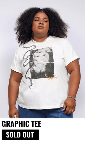 Model with curly black hair looks at camera wearing jeans and The Debbie Harry x Wildfang Graphic Tee. Text underneath image reads GRAPHIC TEE and button underneath reads SOLD OUT.