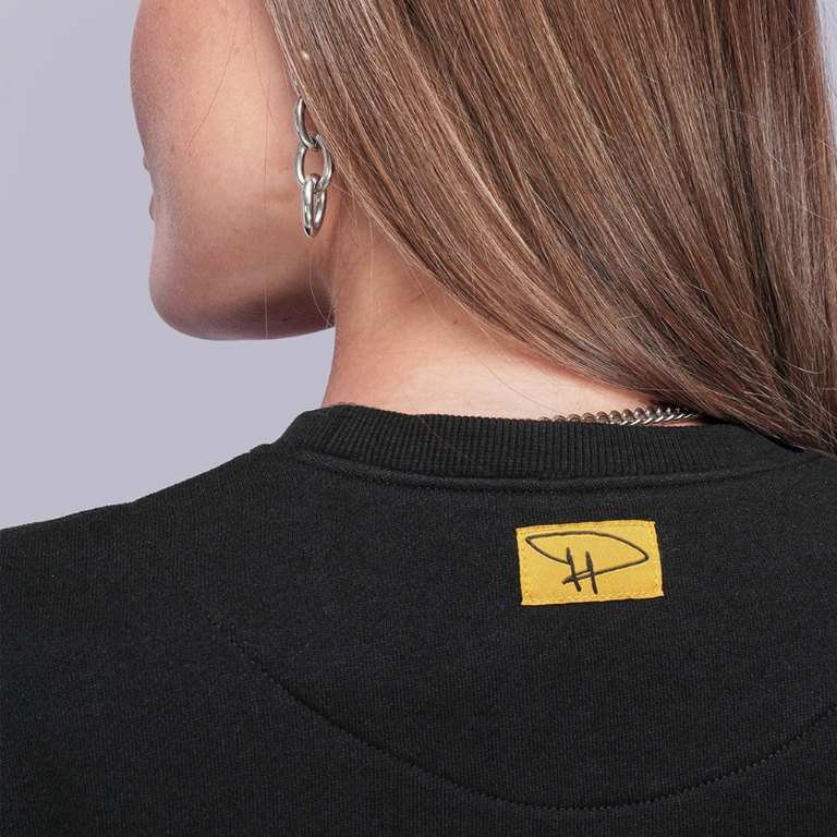 Close-up of a black garment with a yellow label on a gray background