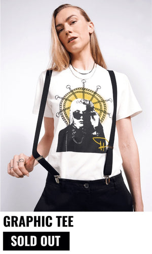 Model with long blonde hair looks at camera wearing suspenders and The Debbie Harry x Wildfang Graphic Tee. Text underneath image reads GRAPHIC TEE and button underneath reads SOLD OUT.