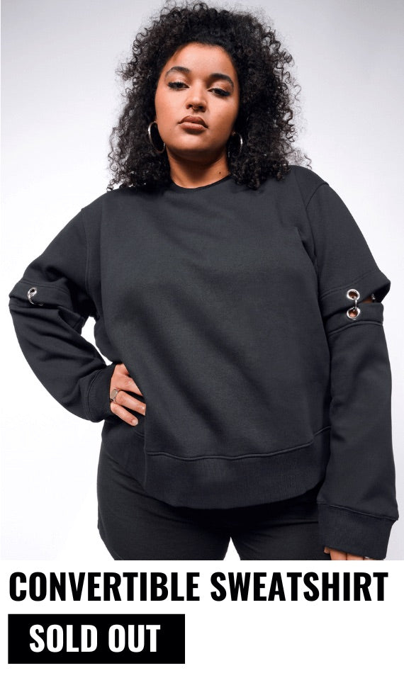 Person with black curly hair looks at camera and is wearing hoop earrings and the Debbie Harry x Wildfang Convertible Sweatshirt. Underneath text reads CONVERTIBLE SWEATSHIRT and button says SOLD OUT