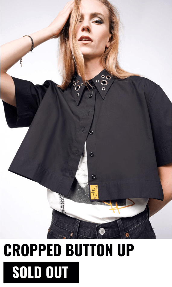 Person with long blonde hair wears t shirt with the black Debbie Harry x Wildfang Cropped Button Up on top, unbuttoned. White background. Text underneath image reads CROPPED BUTTON UP $98 and text underneath reads SOLD OUT.