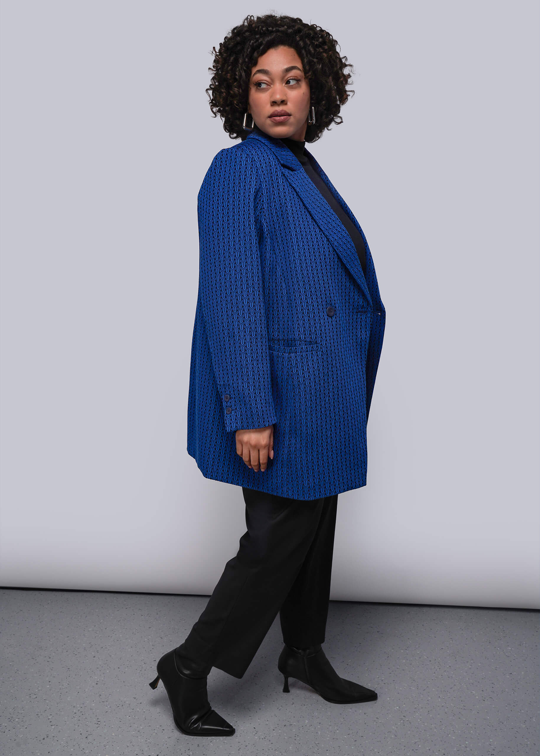 1X=Person wearing a blue blazer and black pants against a white background
