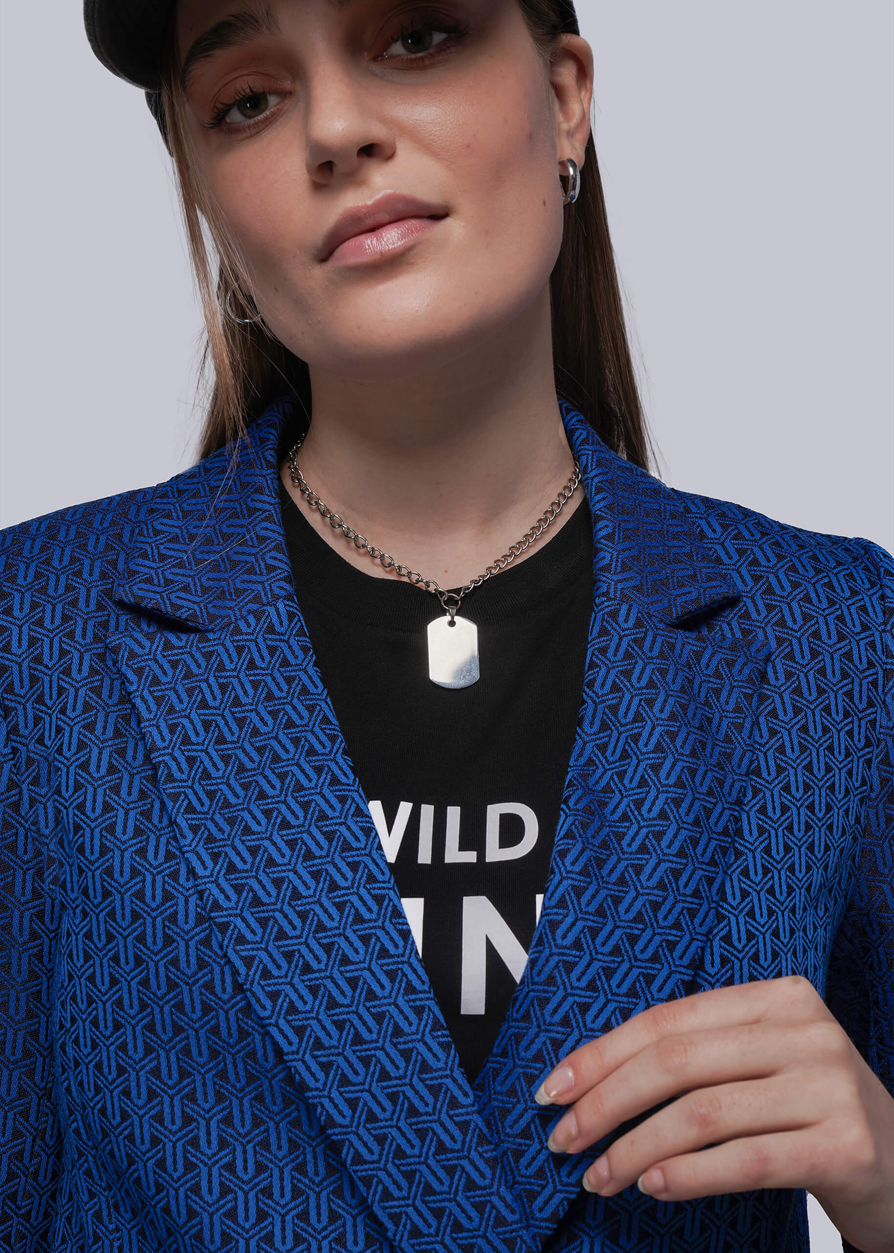 Person wearing a blue patterned blazer over a black shirt with visible text.