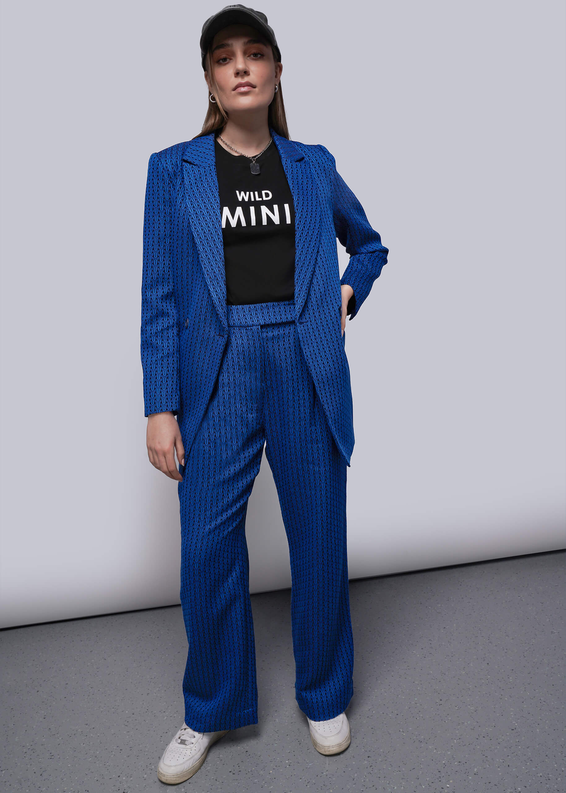 S=Person wearing a blue suit and black graphic shirt with text on a plain background