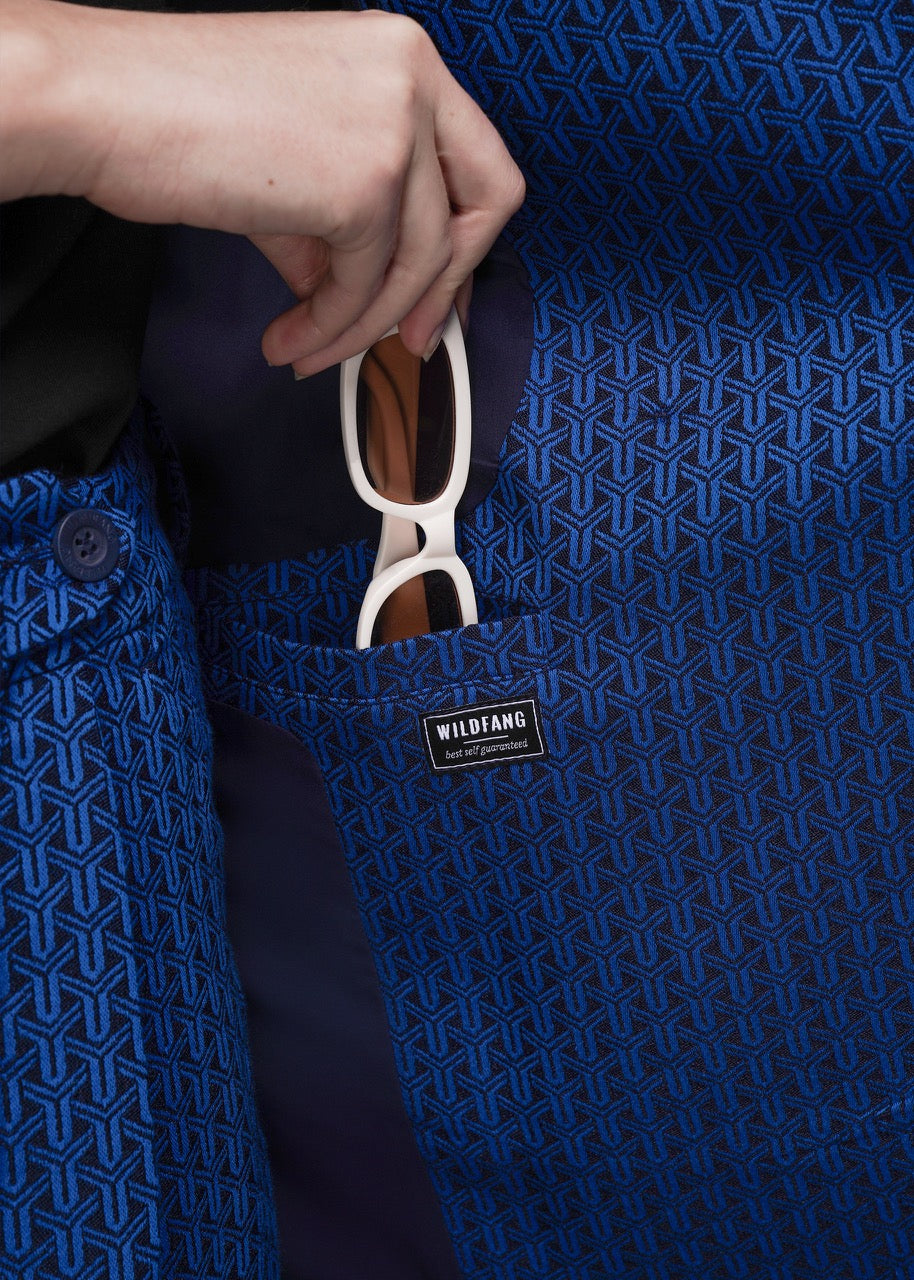 S=Person placing sunglasses in a blue textured blazer pocket with 'WILDFANG' branding.