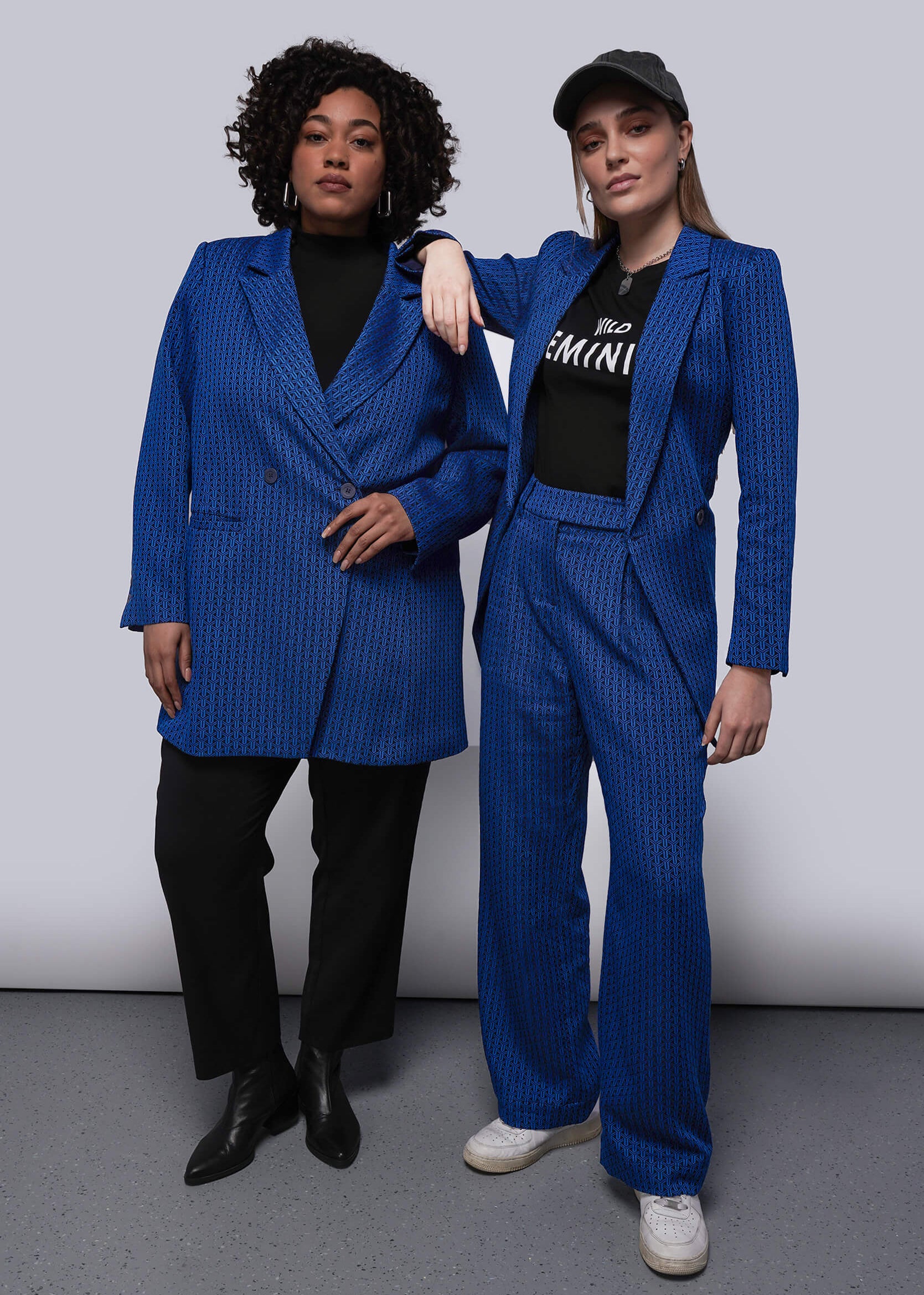 Two people wearing matching blue textured suits against a plain background