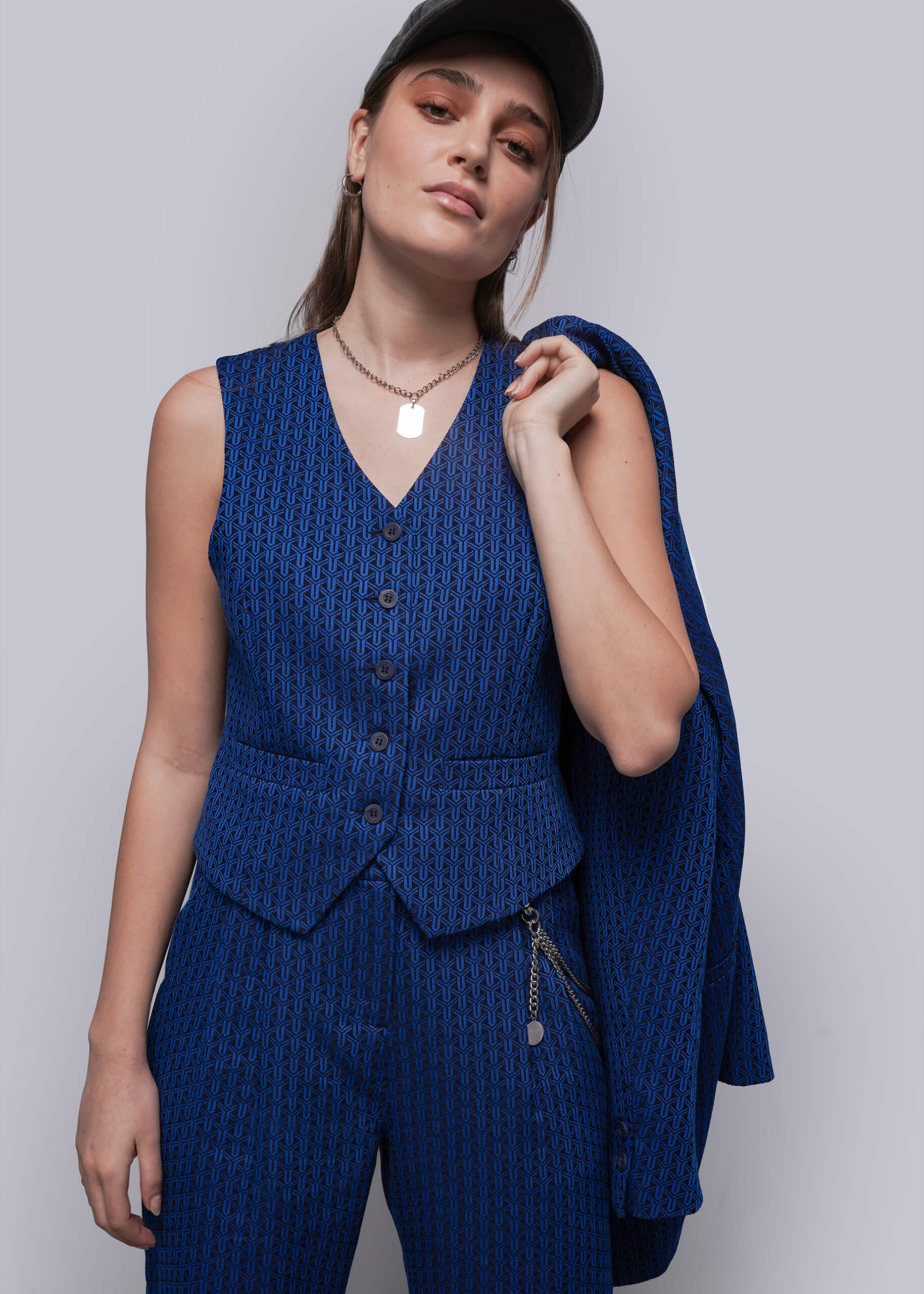 Woman wearing a blue patterned suit with a matching blazer against a plain background