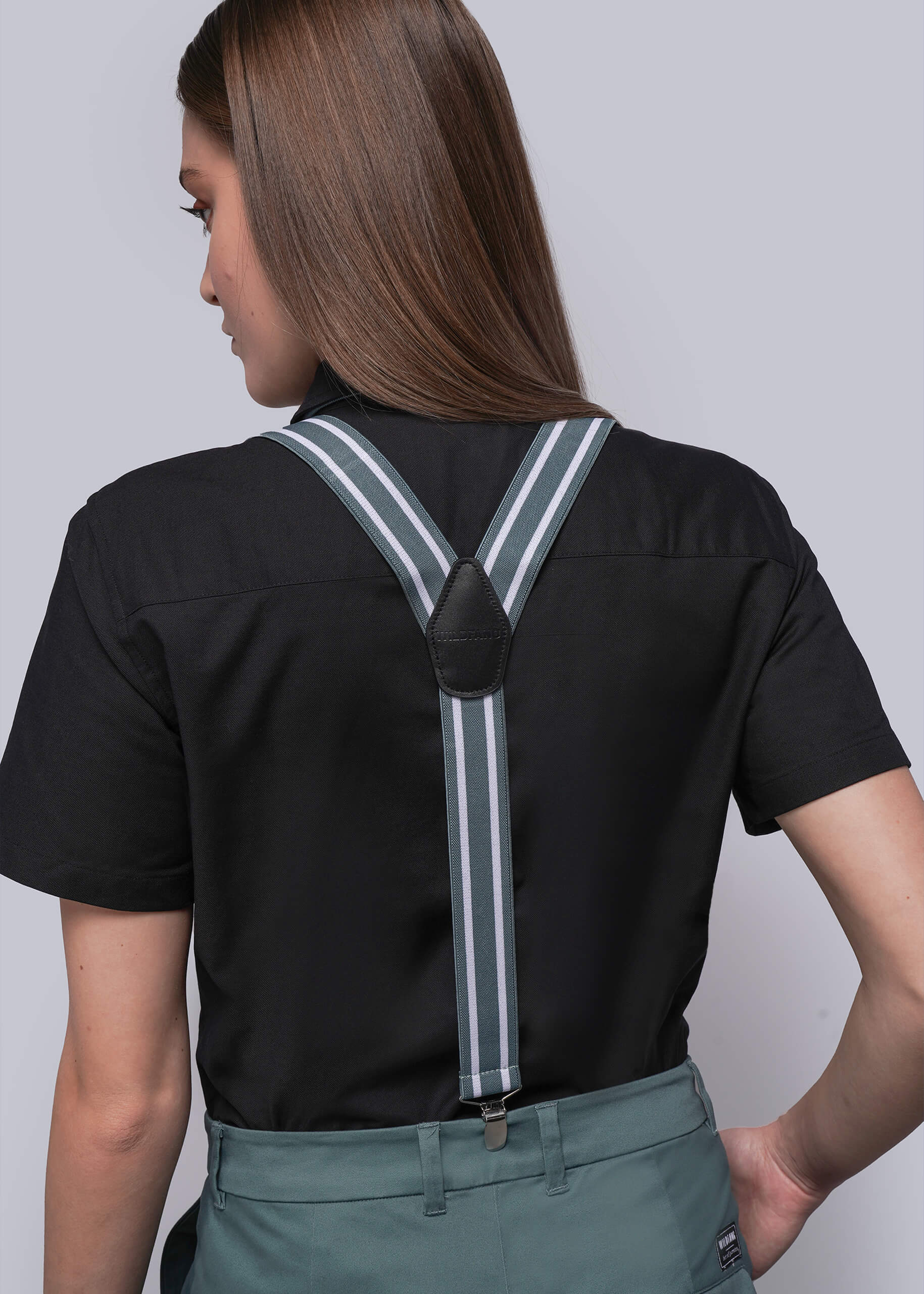Person wearing a black shirt with suspenders on a plain background