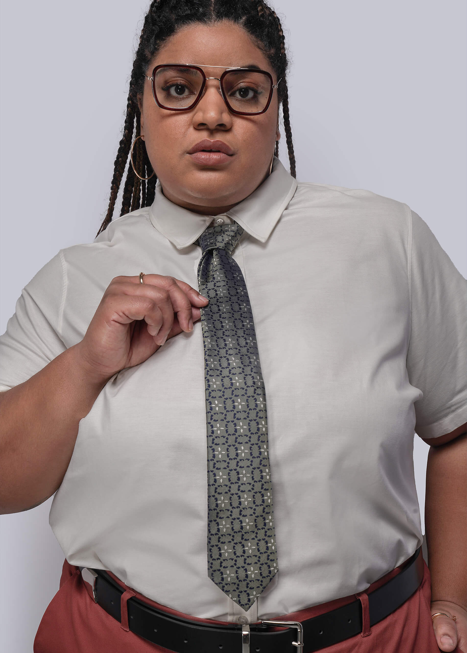 Person wearing a light-colored shirt with a patterned tie against a plain background