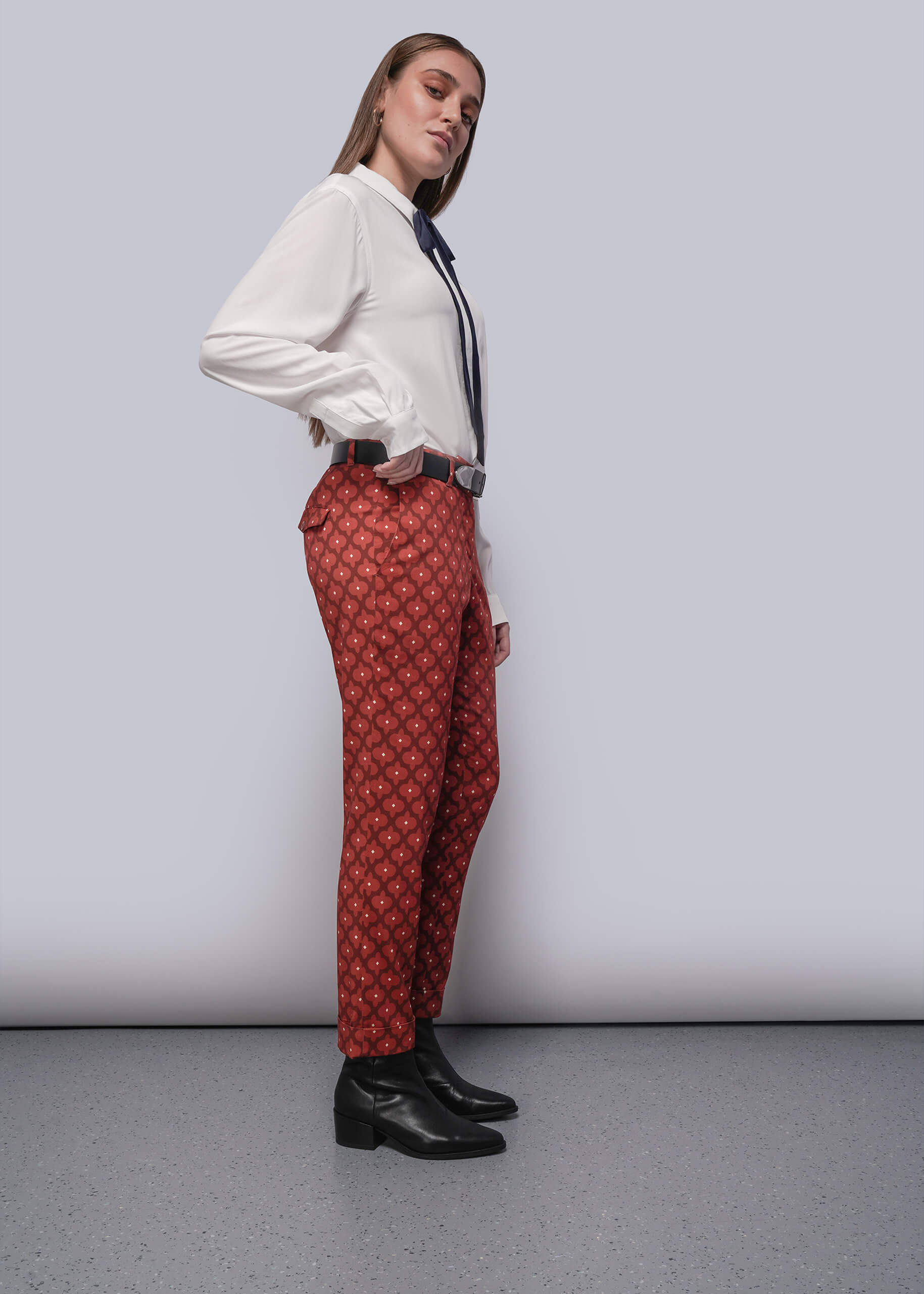 S=Person wearing a white shirt, red patterned pants, and black shoes on a plain background