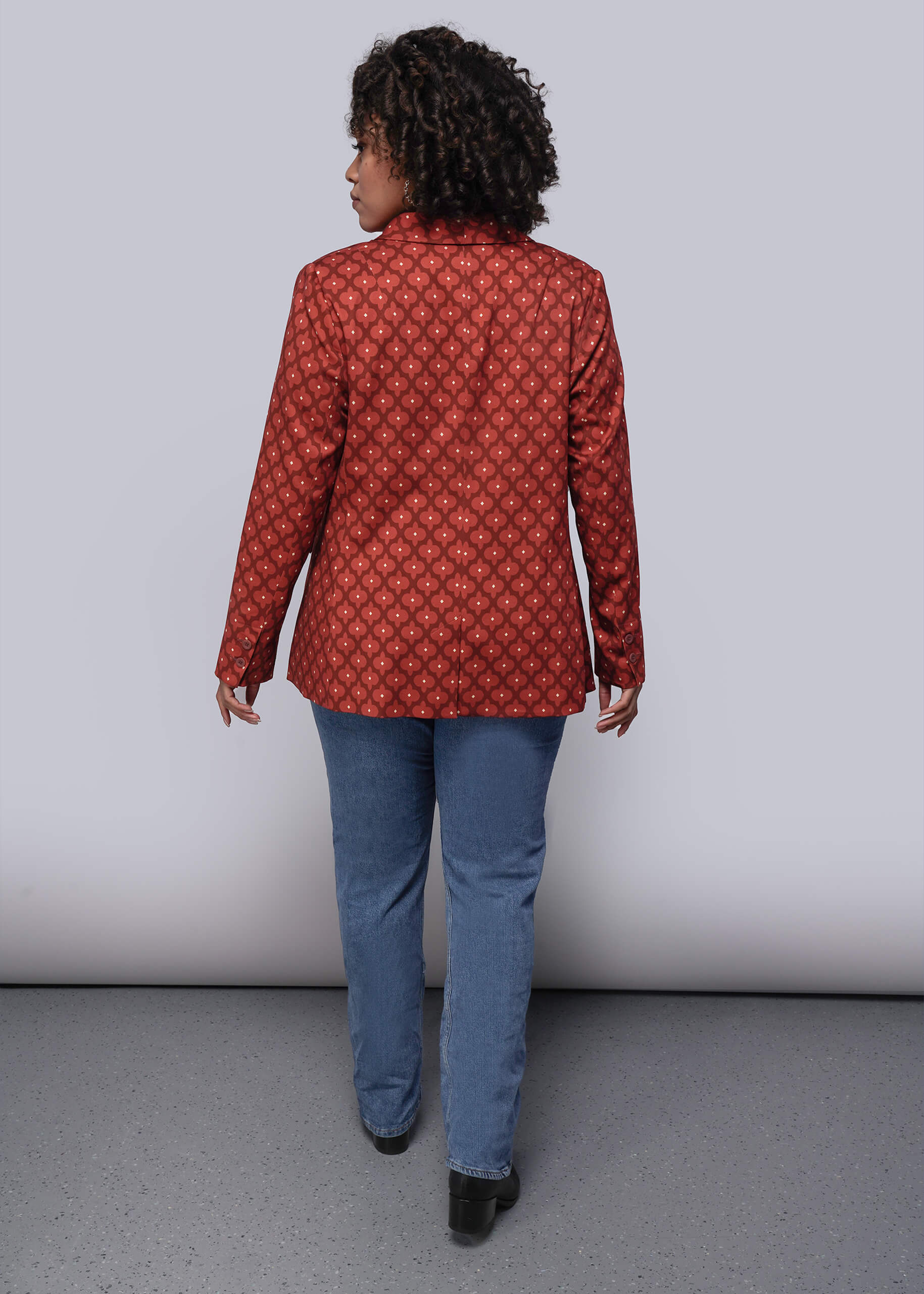 1X=Person wearing a red patterned jacket and blue pants against a plain background