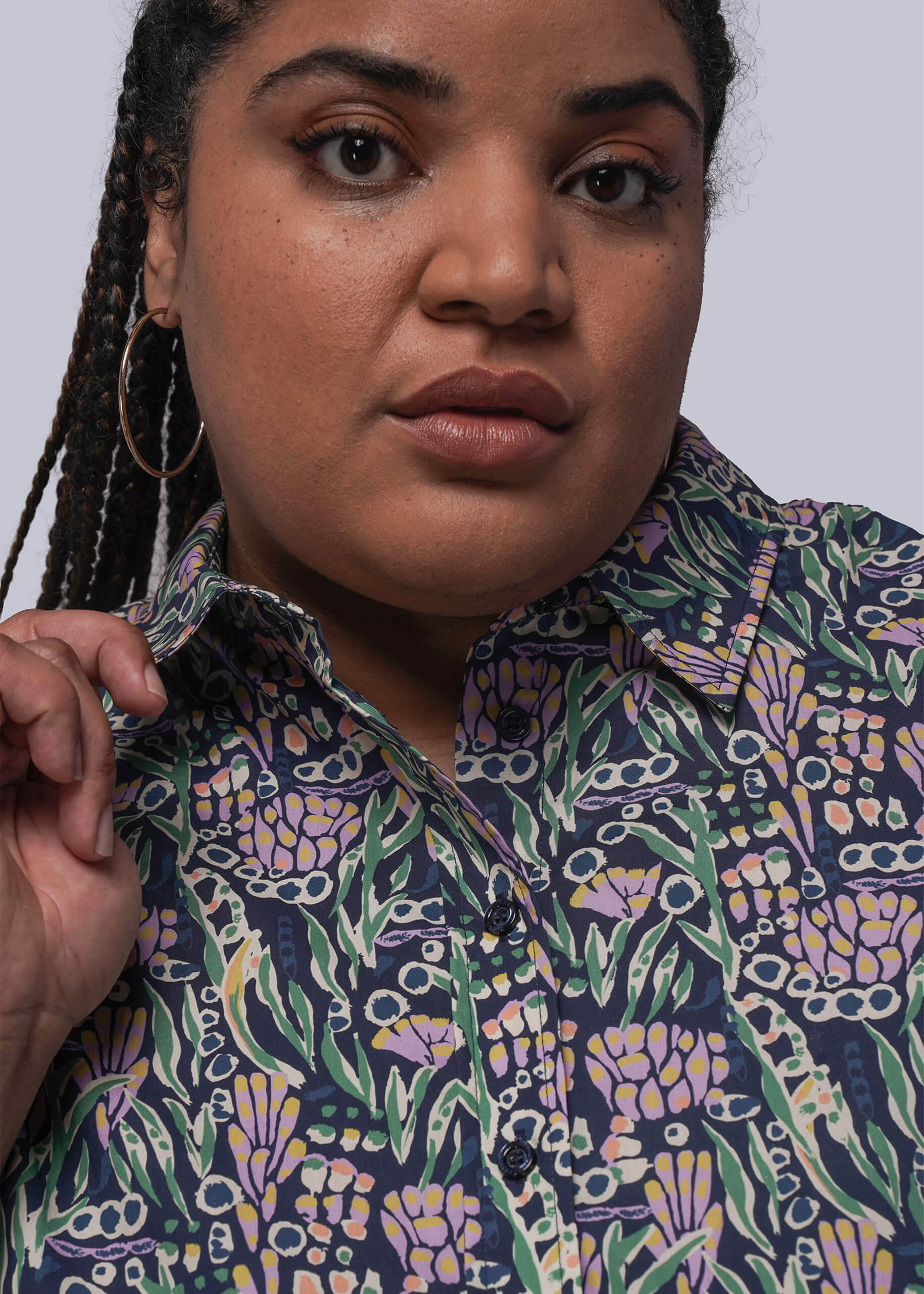 1X=Woman wearing a patterned shirt against a plain background