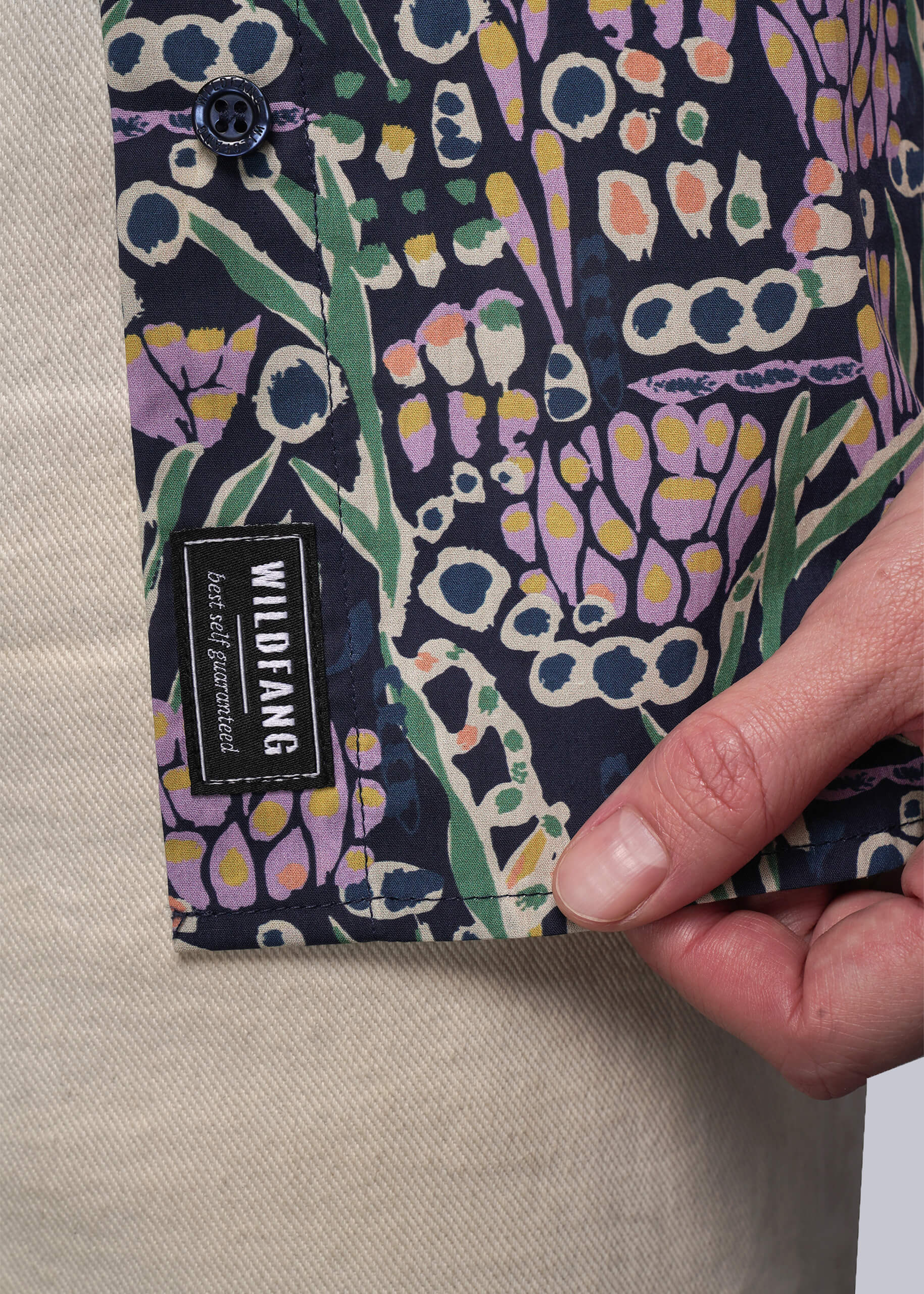 Patterned fabric with a visible brand label held by a hand on a neutral background