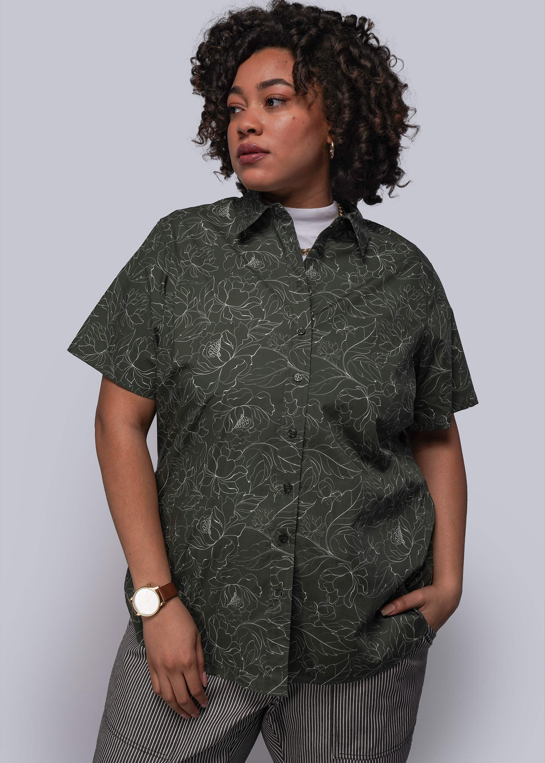 1X=Person wearing a dark green patterned shirt against a plain background