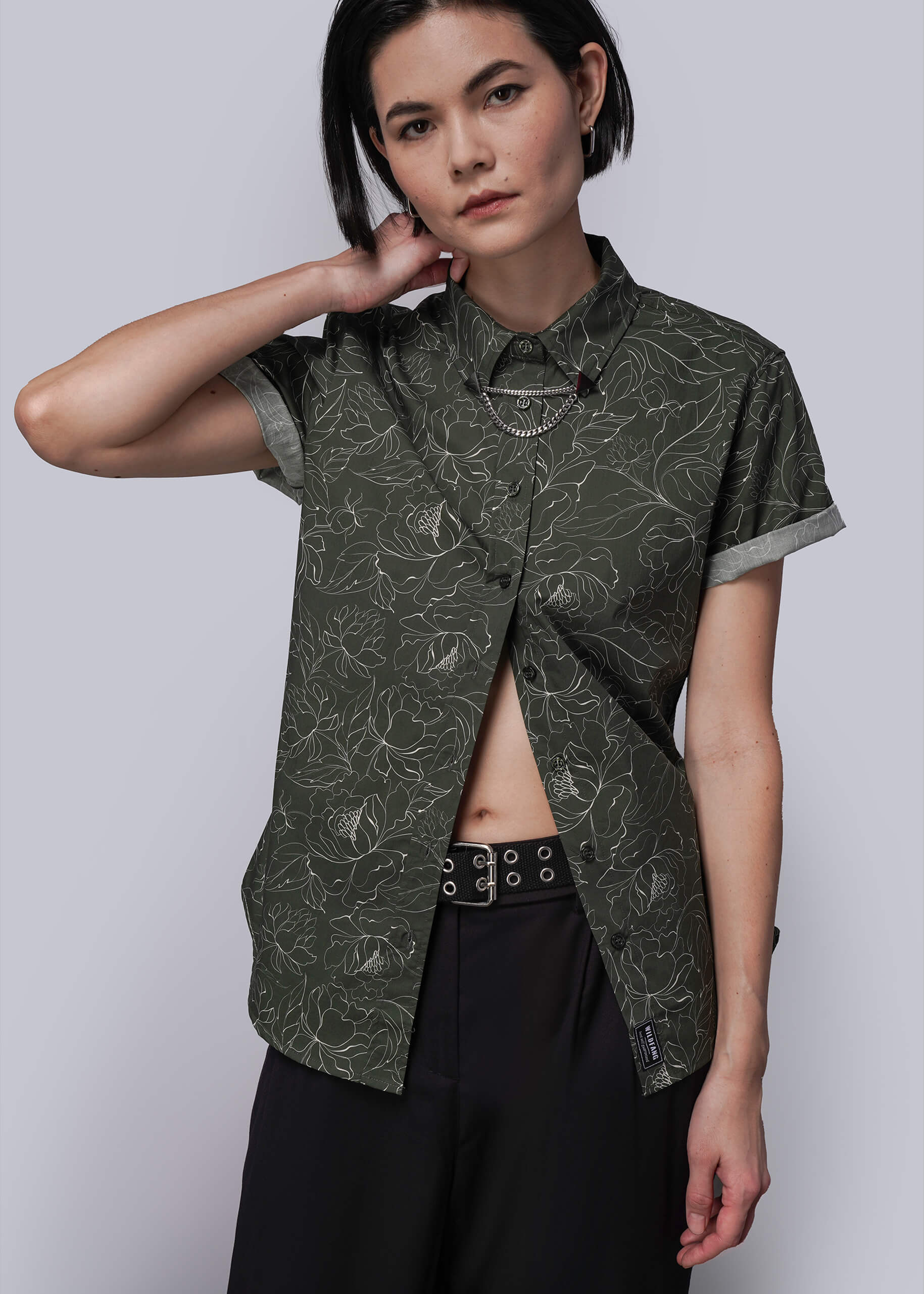 S=Woman wearing a green patterned shirt with a white background