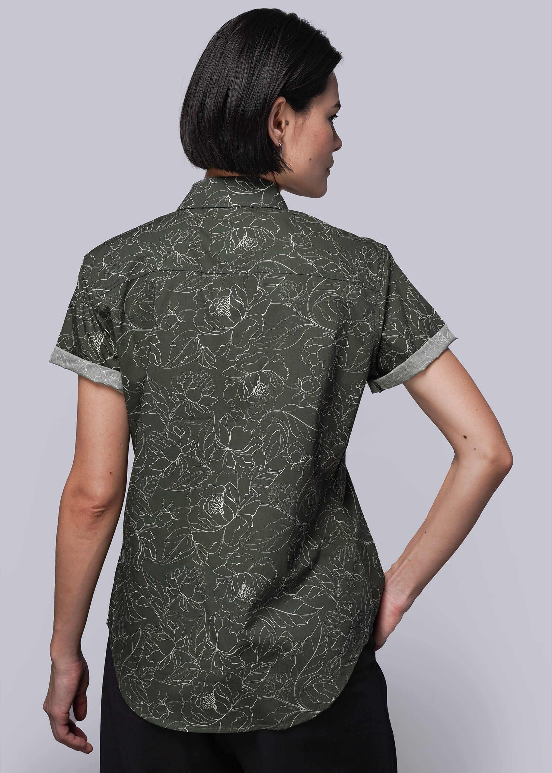 S=Woman wearing a green patterned shirt against a white background